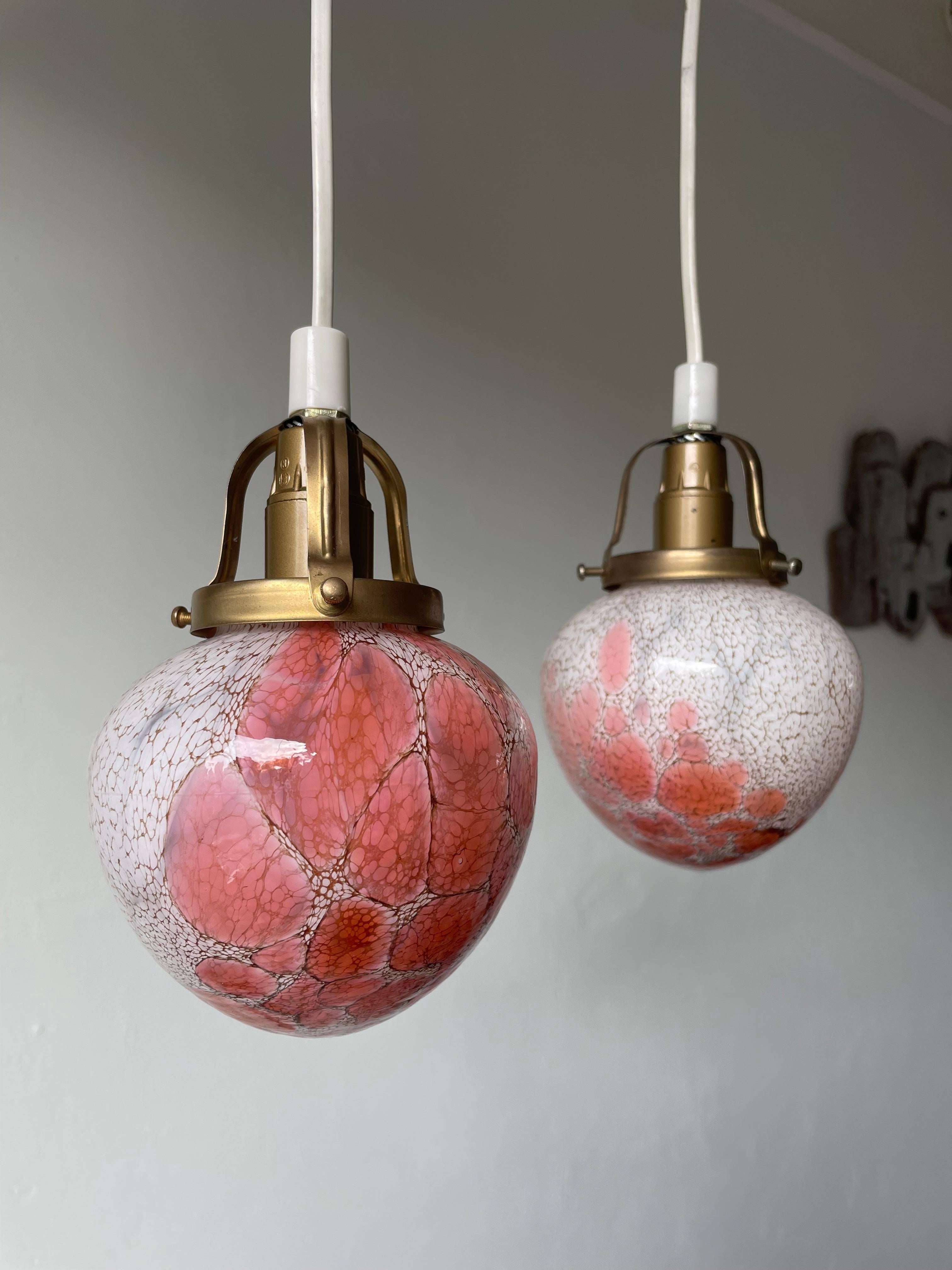 Two striking Scandinavian Modern art glass pendants on brass mounts manufactured by Pukeberg Glassworks in Sweden in the mid 20th century. Cloudy white, rose, pink and peach colors in organic bubble patterns. Small original label on each glass