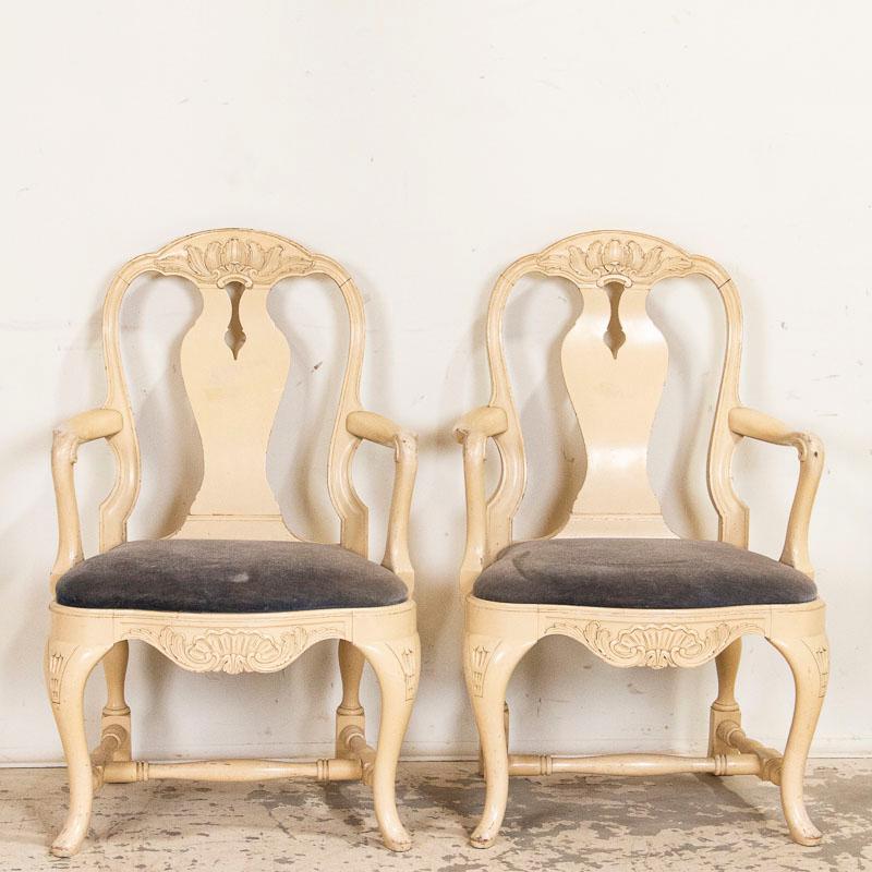 The lovely curves seen in these two arm chairs are reflective of Sweden's love of Rococo styling. Curved backs, cabriolet legs, turned spindles as stretchers and carved details all combine for a romantic look to each chair. The off white painted