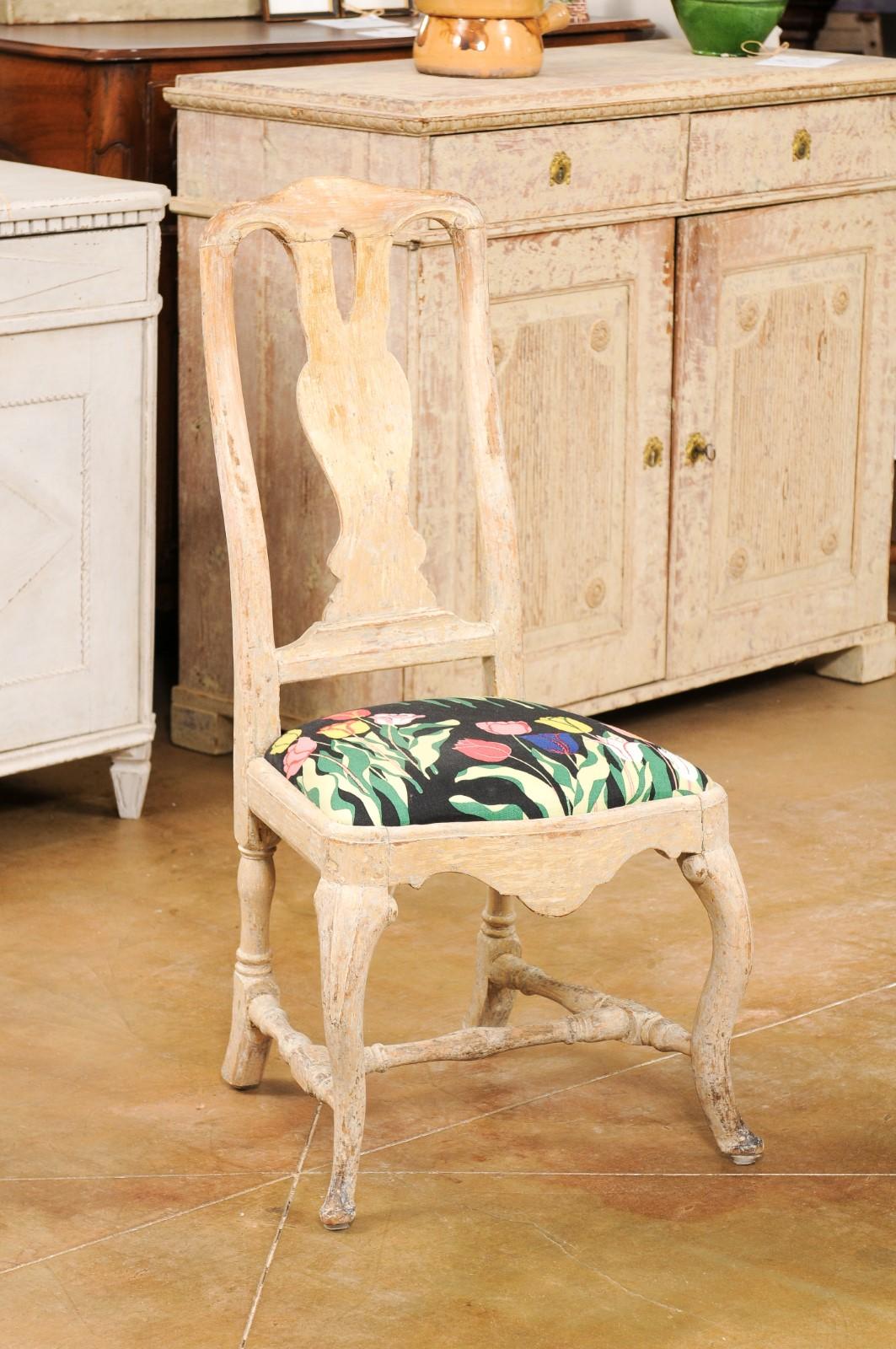 Ein Paar schwedische Rokoko-Stühle aus bemaltem Holz aus dem 18. Jahrhundert, mit geschnitzten Leisten, Cabriole-Beinen, H-förmigen Querstreben, floraler Polsterung und beschädigter Patina. Dieses Paar Beistellstühle aus dem Rokoko wurde im 18.