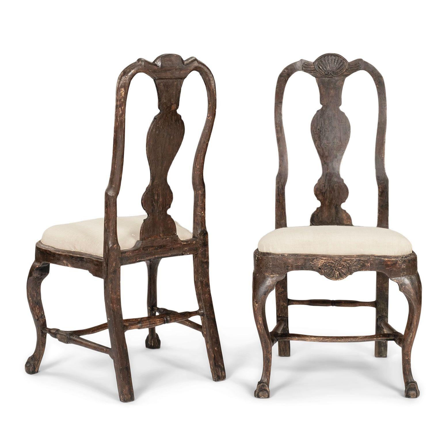 Pareja de sillas suecas de época rococó, talladas a mano hacia 1745-1774. Acabado suavemente raspado hasta las primeras capas de pintura originales. Motivo de concha tallado en el friso y la cresta. Patas delanteras cabriolé que descansan sobre pies