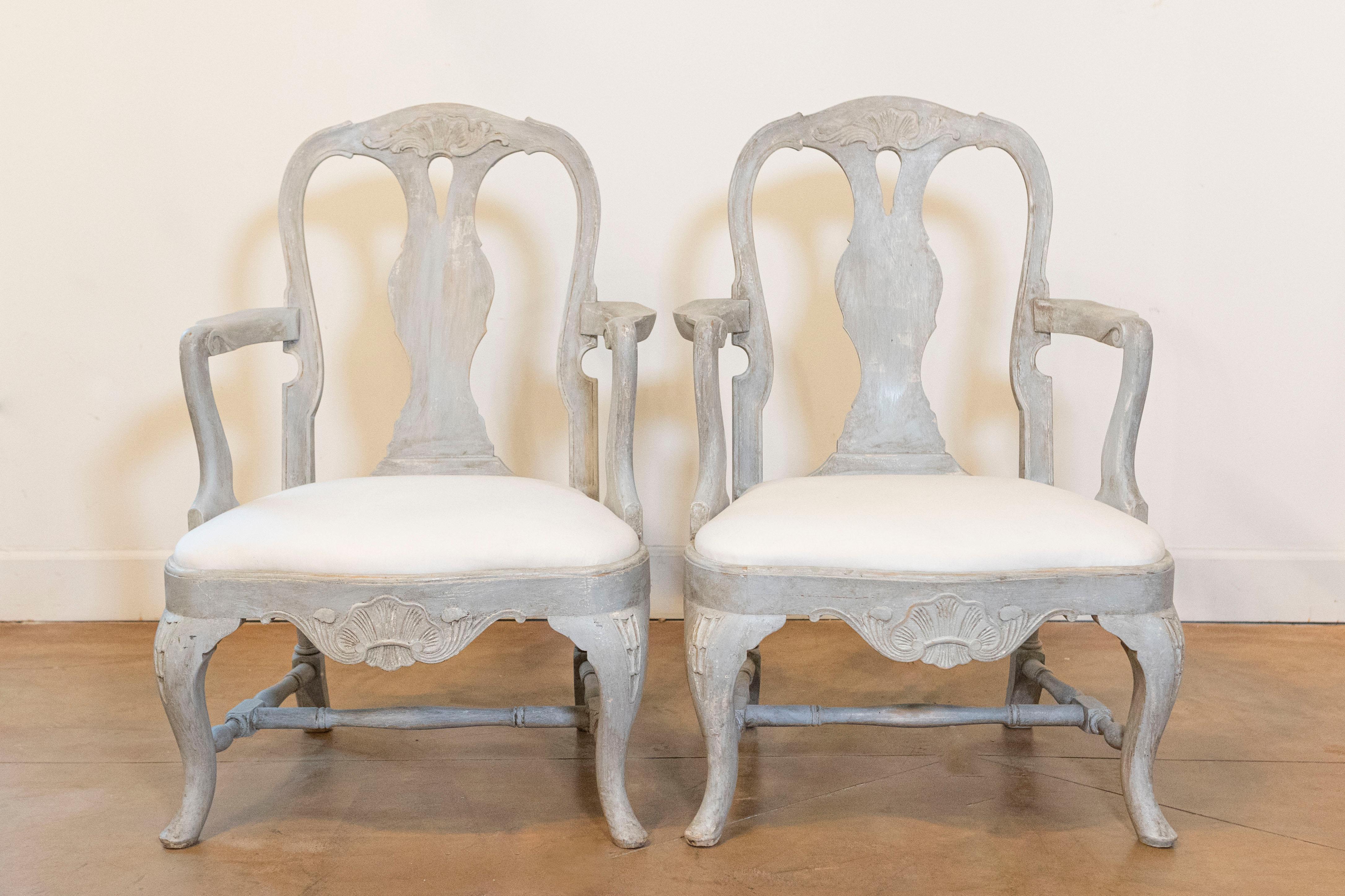 Coppia di poltrone in legno dipinto in stile rococò svedese della fine del XIX secolo, con stecche intagliate, gambe a cabriola e imbottitura. Creata in Svezia nell'ultimo decennio del XIX secolo, questa coppia di poltrone in stile rococò presenta