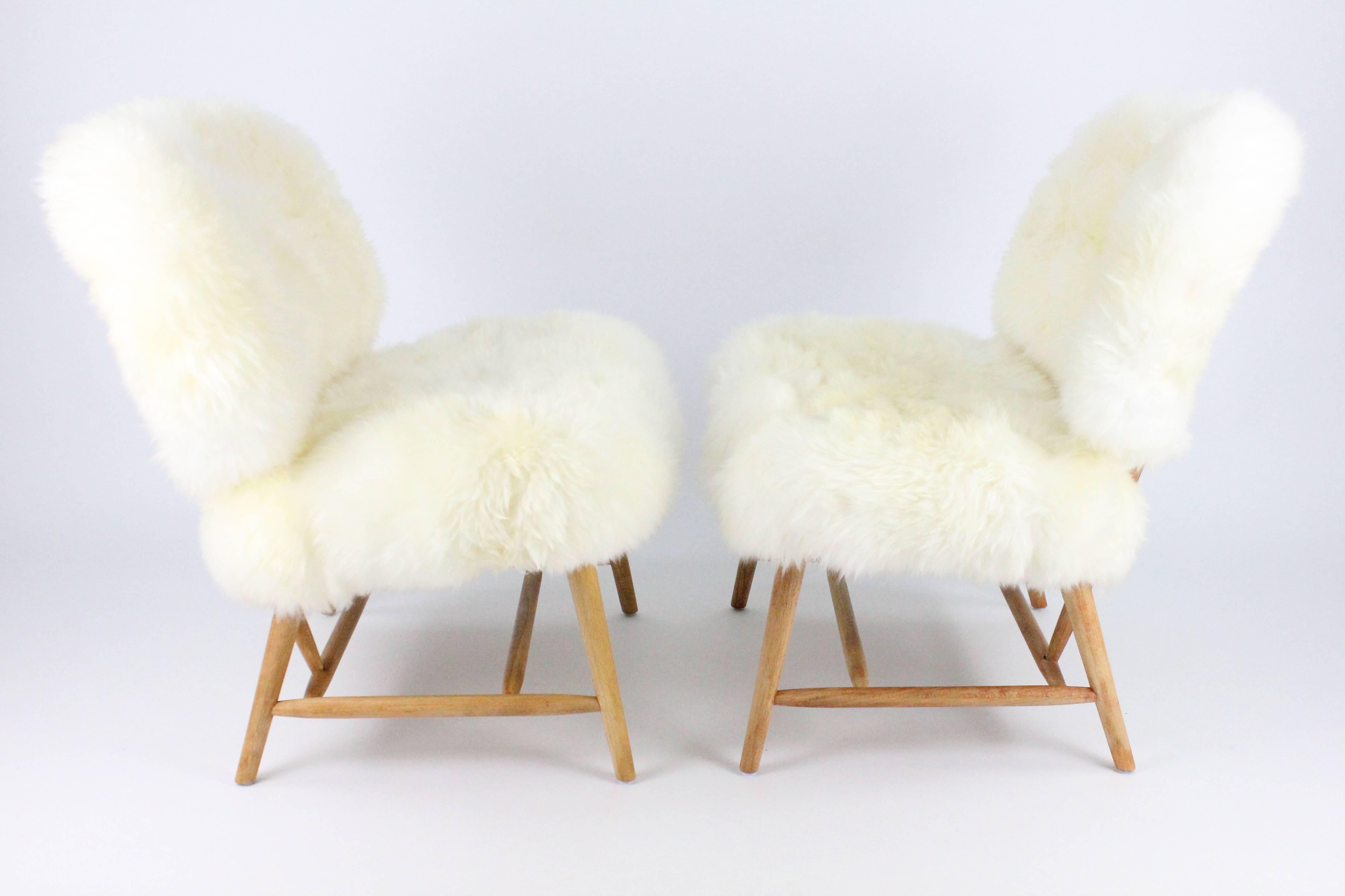A wonderful pair of Teve easy chairs upholstered in Sheepskin. Designed by Alf Svensson in 1953. Manufactured by Ljungs Industrier for DUX. The frame is in oiled beech and they are recently upholstered in off-white long hair sheepskin. Very nice