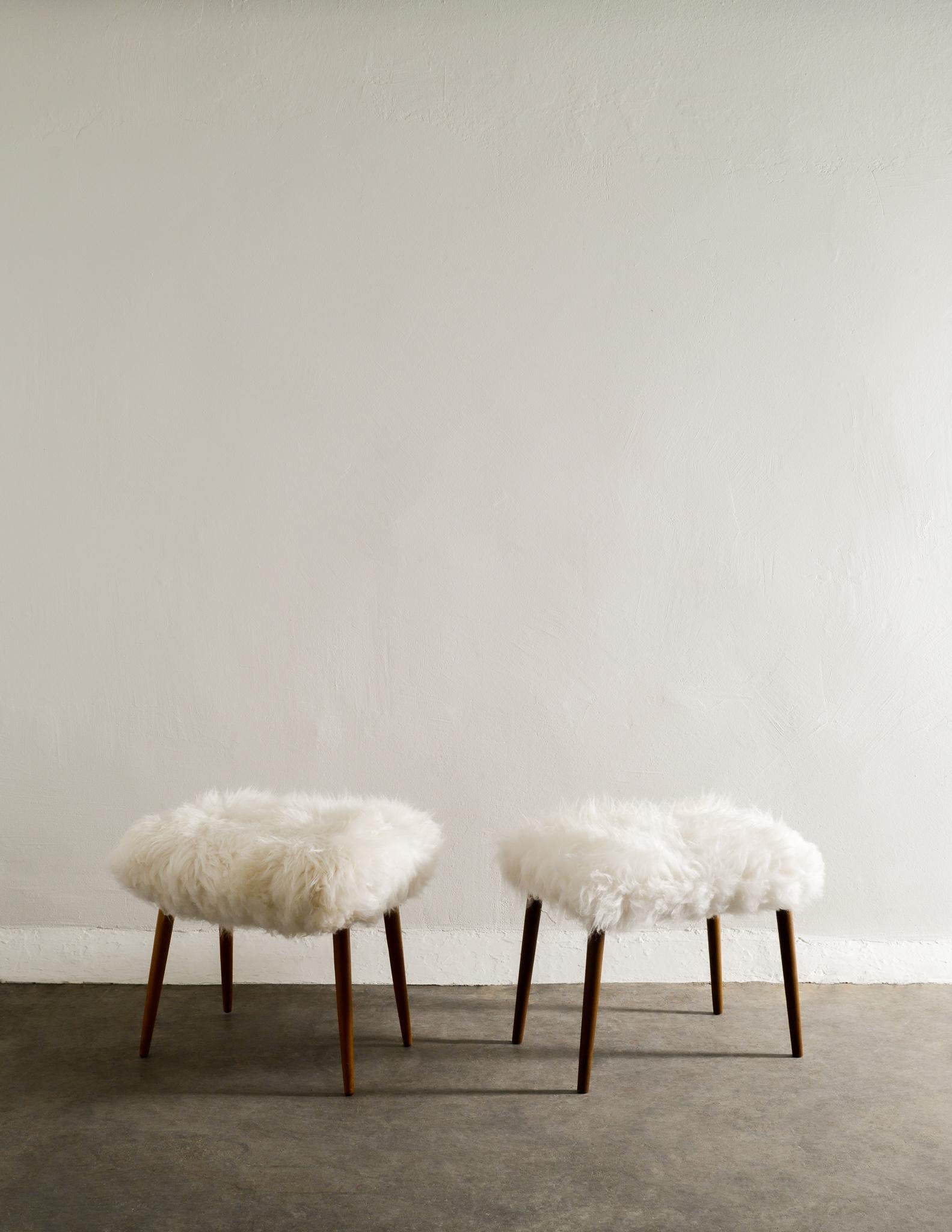 Rare pair of Swedish stools in beech newly upholstered in white fluffy sheepskin. In good vintage condition with minimal signs of use. Sold as a pair. 

Dimensions: H: 43 cm W: 56 cm D: 40 cm.