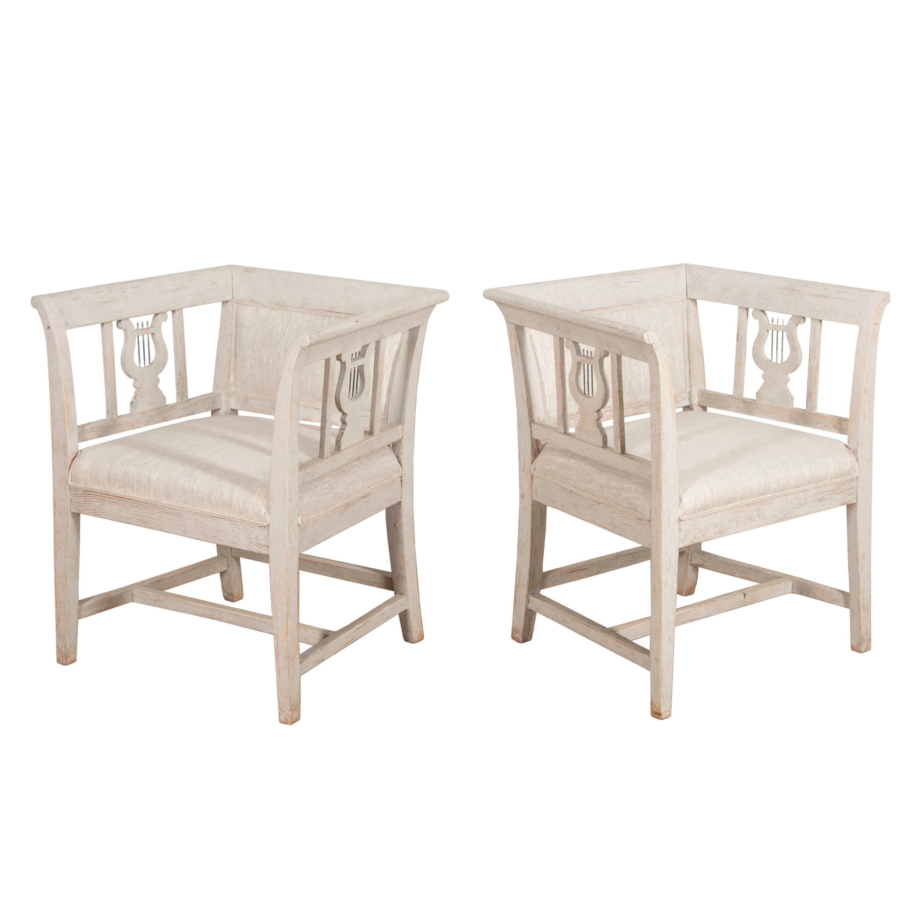 Pair of Gustavian style armchairs with decorative lyres on both sides.
These wonderful pair of chairs have been later painted and newly upholstered in neutral coloured linen. 
Originally, these chairs were used as veranda chairs within a Swedish