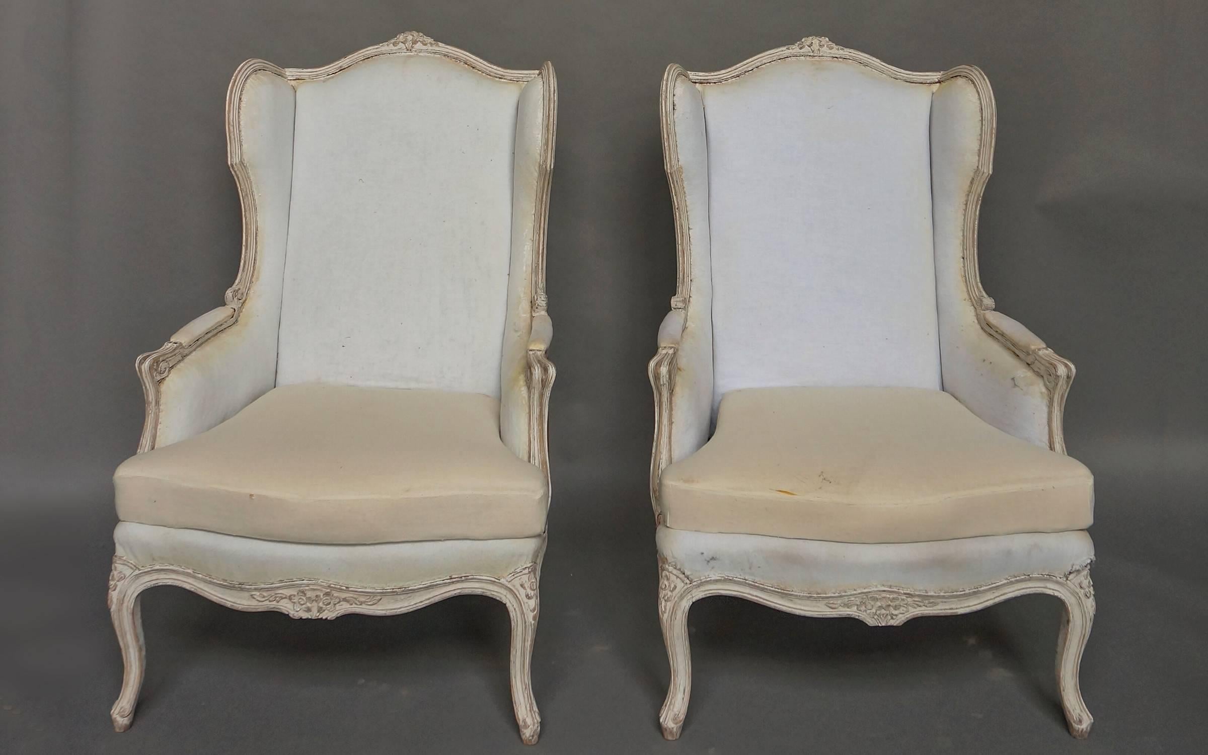 Pair of roomy wing-back chairs, Sweden circa 1910, in the Gustavian style. The exposed wooden frame is carved with roses at the top, on the apron, and on the “knees” of the cabriole legs. Very Swedish indeed.