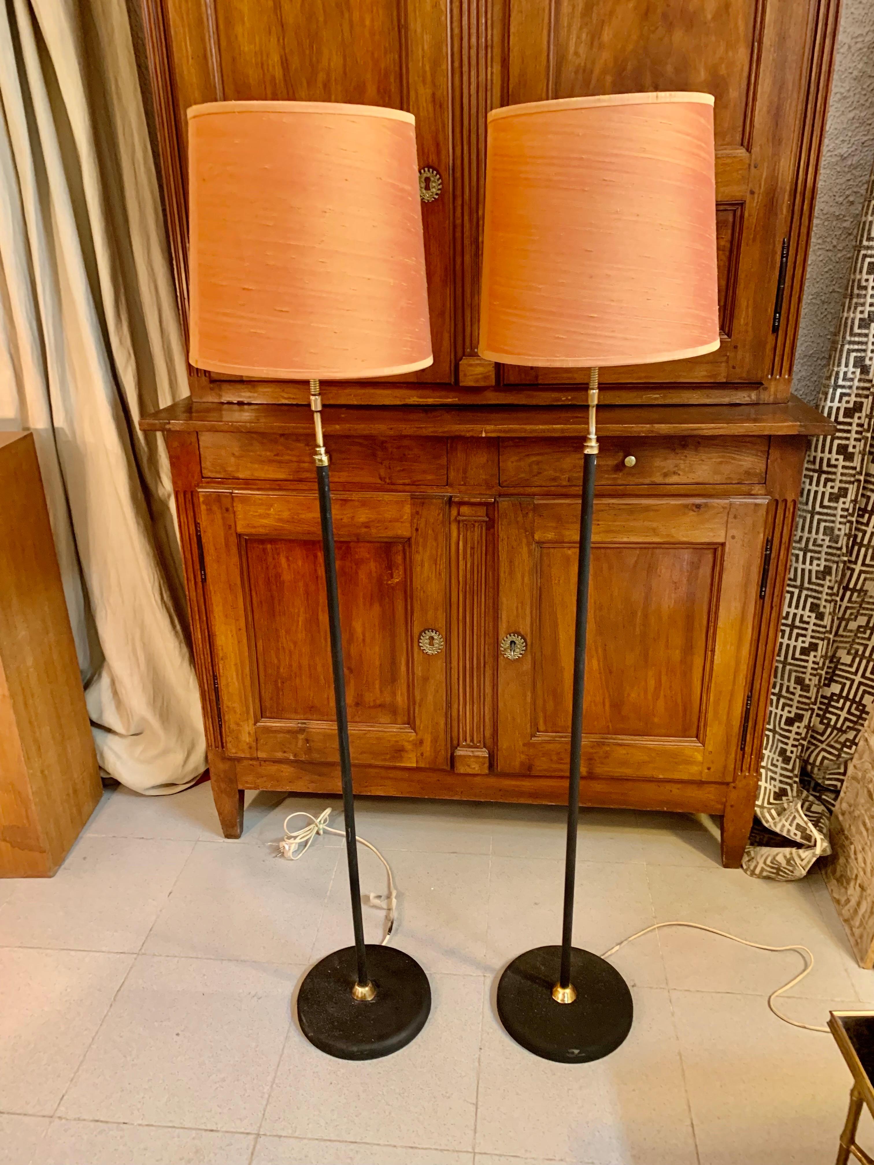 Set of two mid-century floor lamps was made in Sweden in the 1960s by Stilarmatur. The lamps consist of a black lacquered metal foot with a small brass cone, from where the black lacquered column begins. The lampshades rest on an adjustable brass