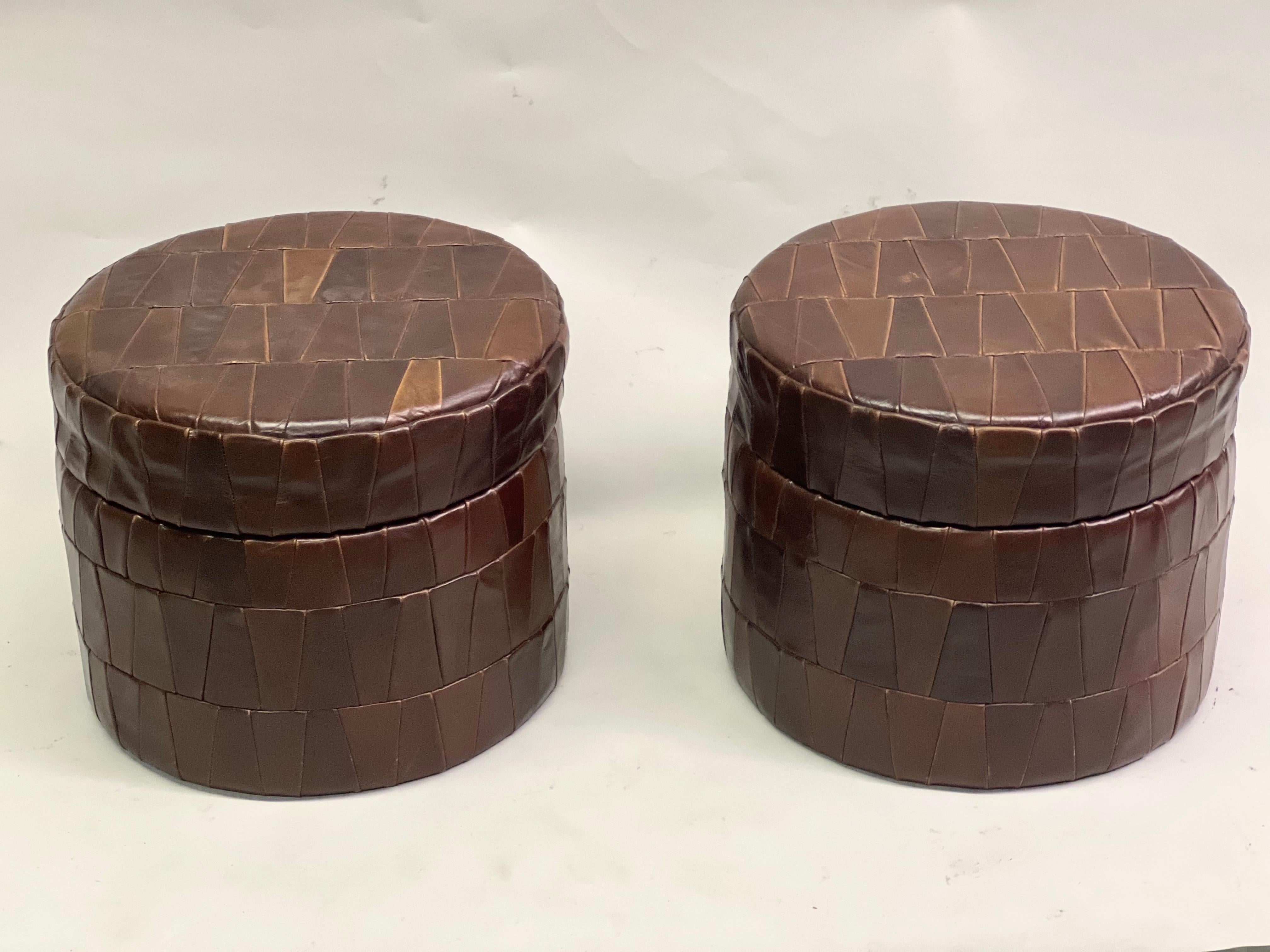 Pair of Finely Crafted Swiss Mid-Century Modern Ottomans / Poufs / Stools / Benches by De Sede, Switzerland circa 1960. This matched pair is round / circular and features De Sede's iconic stitching and patchwork design. Each piece opens to reveal a