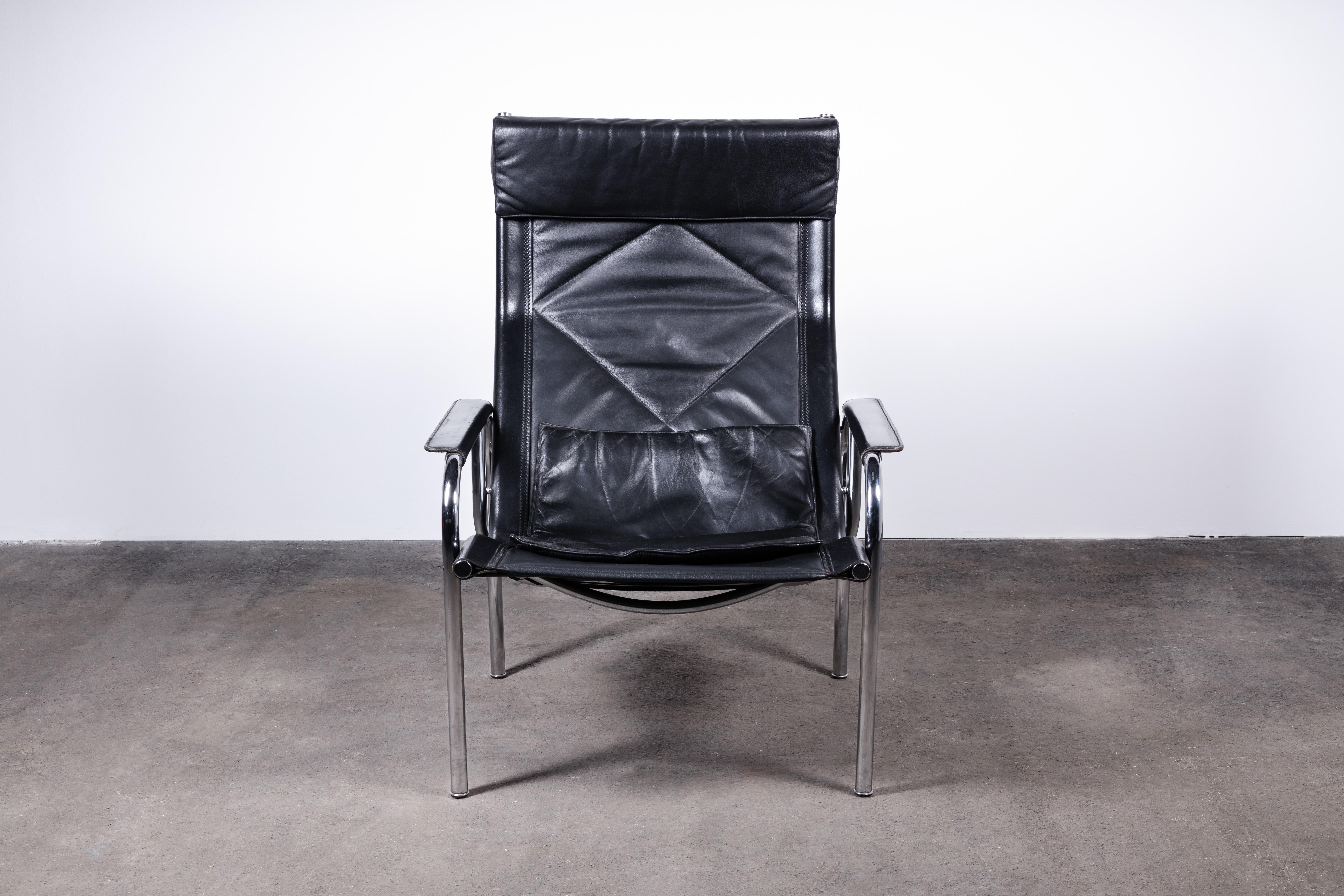 Mid-Century Modern pair of high-back reclining chairs in black leather and chromed tubed steel. Made in Switzerland by Strässle International and designed by Hans Eichenberger. Both lounge chairs feature leather seat cushions as well as vertically