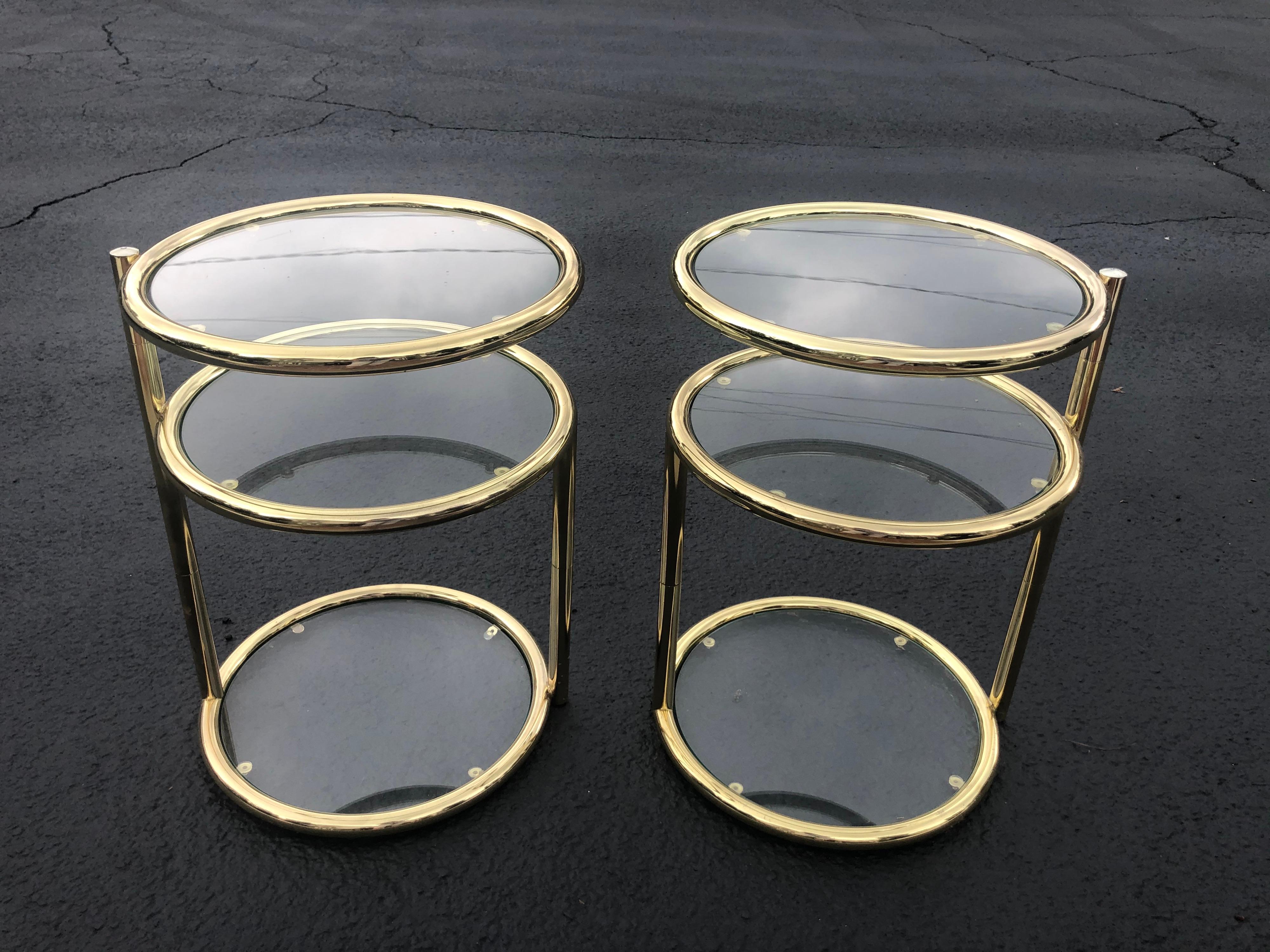 Pair of Swivel brass and glass end tables. Retro three tier side tables that can expand to be wider. Price is for the pair of 2 total. 
White glove is recommended for these table. Parcel shipping is not recommended due to fragility and moving parts.