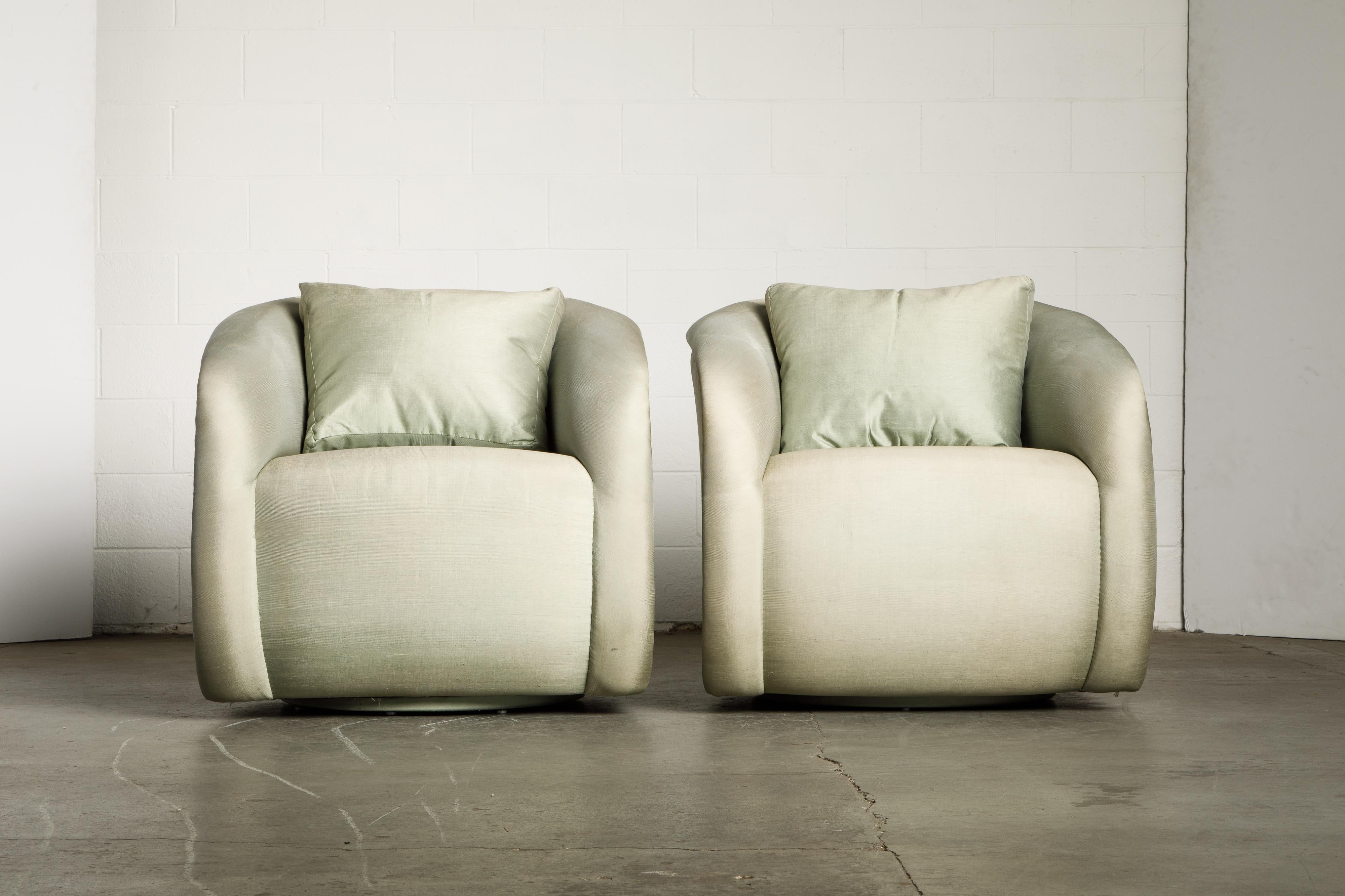This pair of swivel chairs attributed to Milo Baughman for Directional is upholstered in a light mint green silk fabric with removable loose cushions. Circa 1980s, this pair of club chairs was reupholstered previously and have had moderate use since