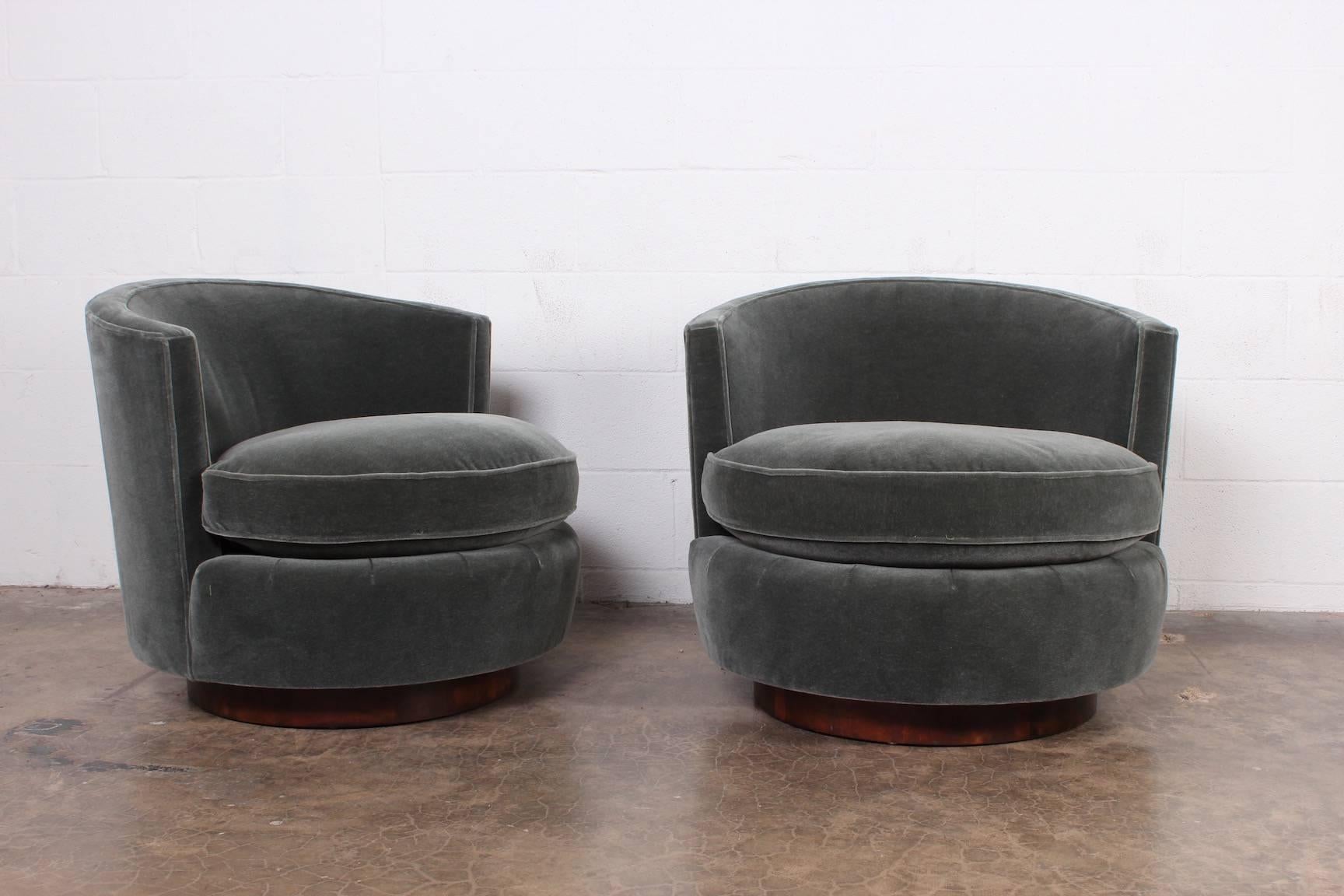 A pair of swivel chairs with walnut plinth bases. Designed by Edward Wormley for Dunbar. Fully restored and upholstered in mohair with down seat cushions.