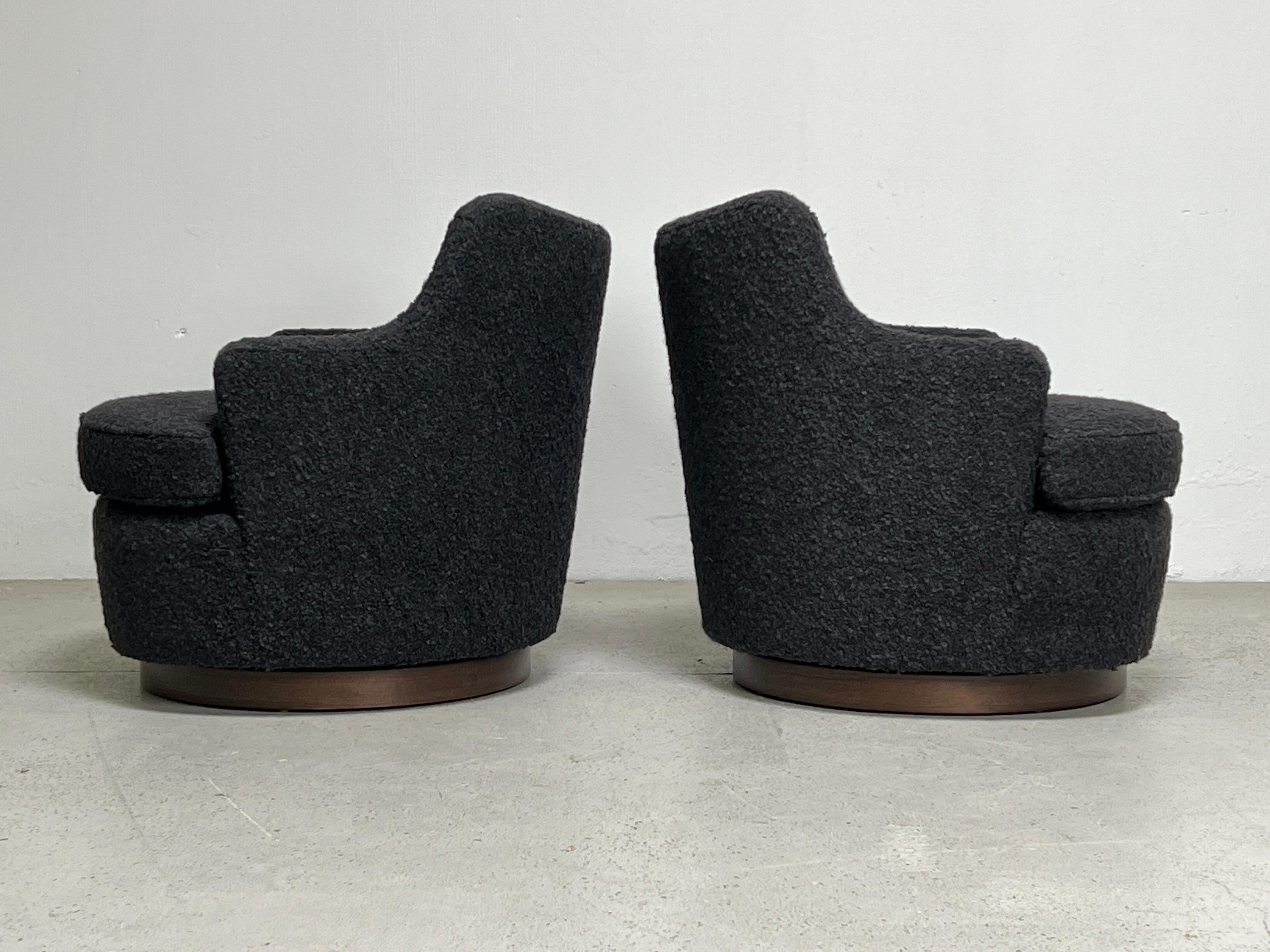 A pair of dunbar swivel chairs designed by Edward Wormley with walnut bases. Newly upholstered in holly hunt / teddy / charcoal fabric.