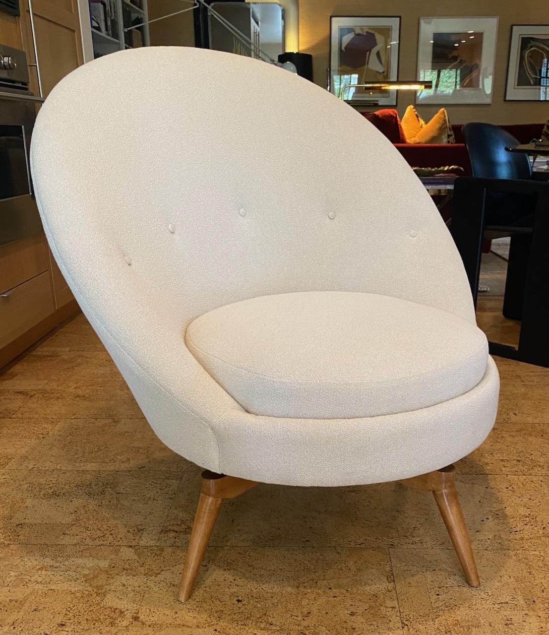 Dramatic and sculptural pair of swivel chairs upholstered in luxurious off-white Boucle with the bases in natural maple finish. These chairs are handcrafted of the finest materials and swivel quietly and smoothly on nylon ring bearing swivel plates.