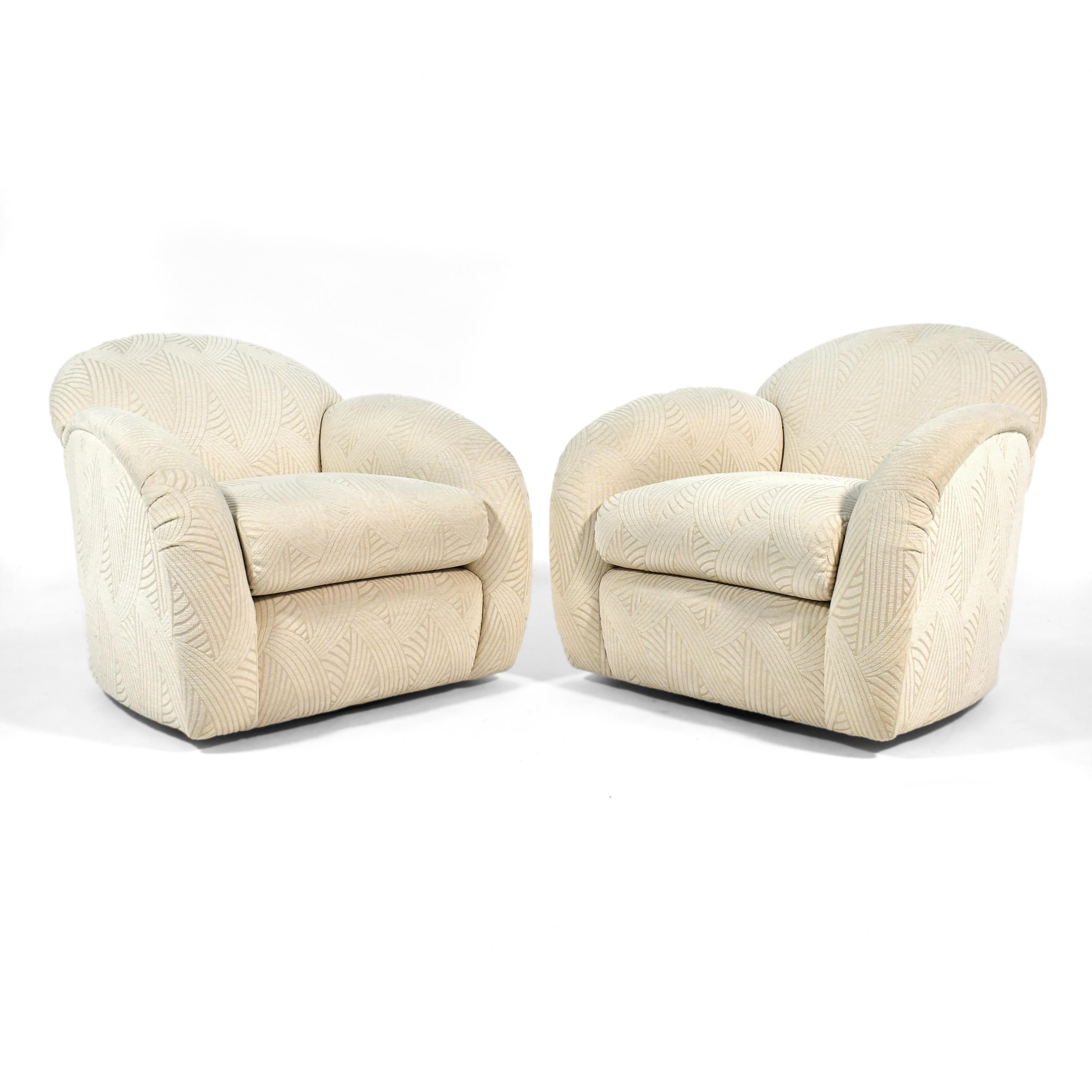 This handsome pair of lounge chairs have an elegant and dynamic shape. They have swivel function, with the recessed base lending them a floating appearance. They were expertly crafted by Interior Crafts in Chicago and are upholstered in a patterned