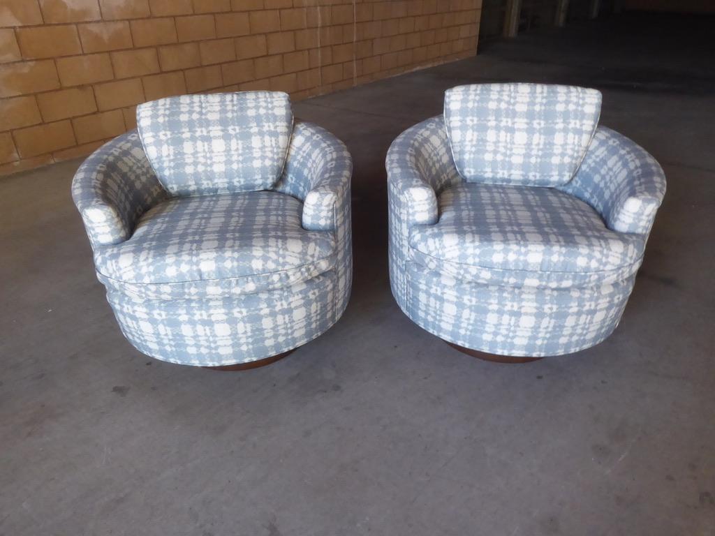 A pair of newly upholstered swiveling club chairs from the 1980s. Each of the chairs is raised on a tall mahogany base, circa 1980s.