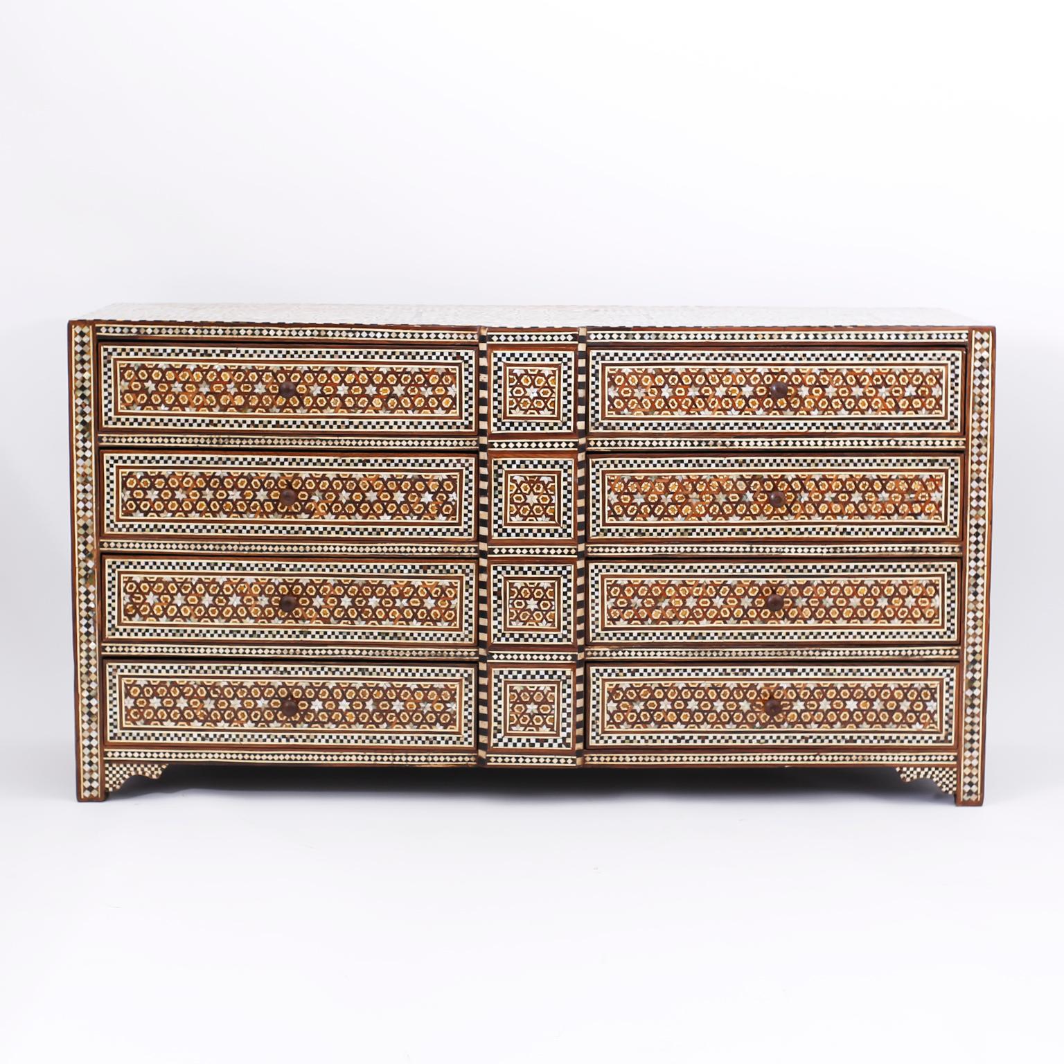 Pair of Syrian mahogany chests of drawers or eight-drawer commodes completely clad with inlaid and marquetry mother of pearl, bone, and ebony panels composed in geometric designs with elaborate borders. The sides have inset panels and the feet have