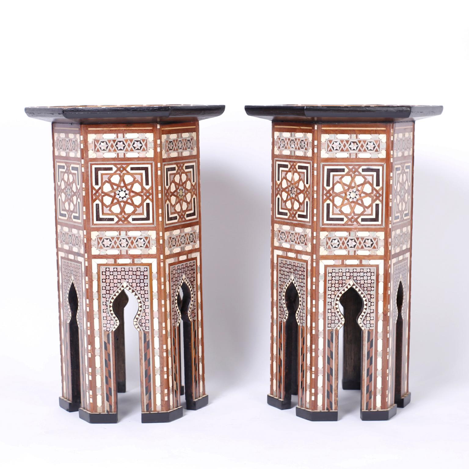 Pair of antique Syrian stands with a hexagon form crafted in mahogany with dramatic geometric inlays of mother of pearl, ebony, kingwood, and bone on the tops and all sides. The legs have architecturally interesting Moorish arches on block feet.