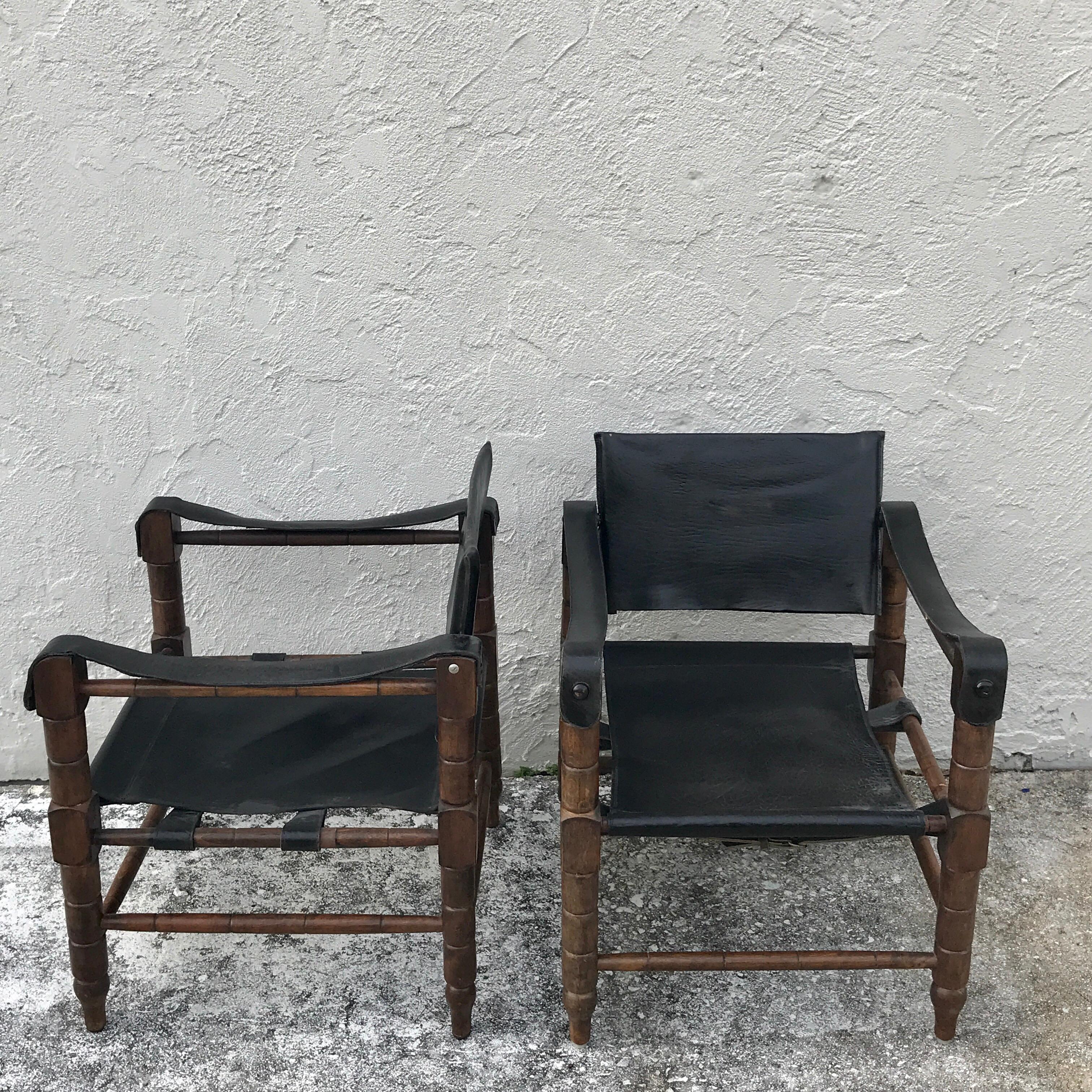 Pair of Syrian leather Campaign / Safari chairs, each one with subtly carved wood frames with black leather upholstery. Measures: Arm height is 24
