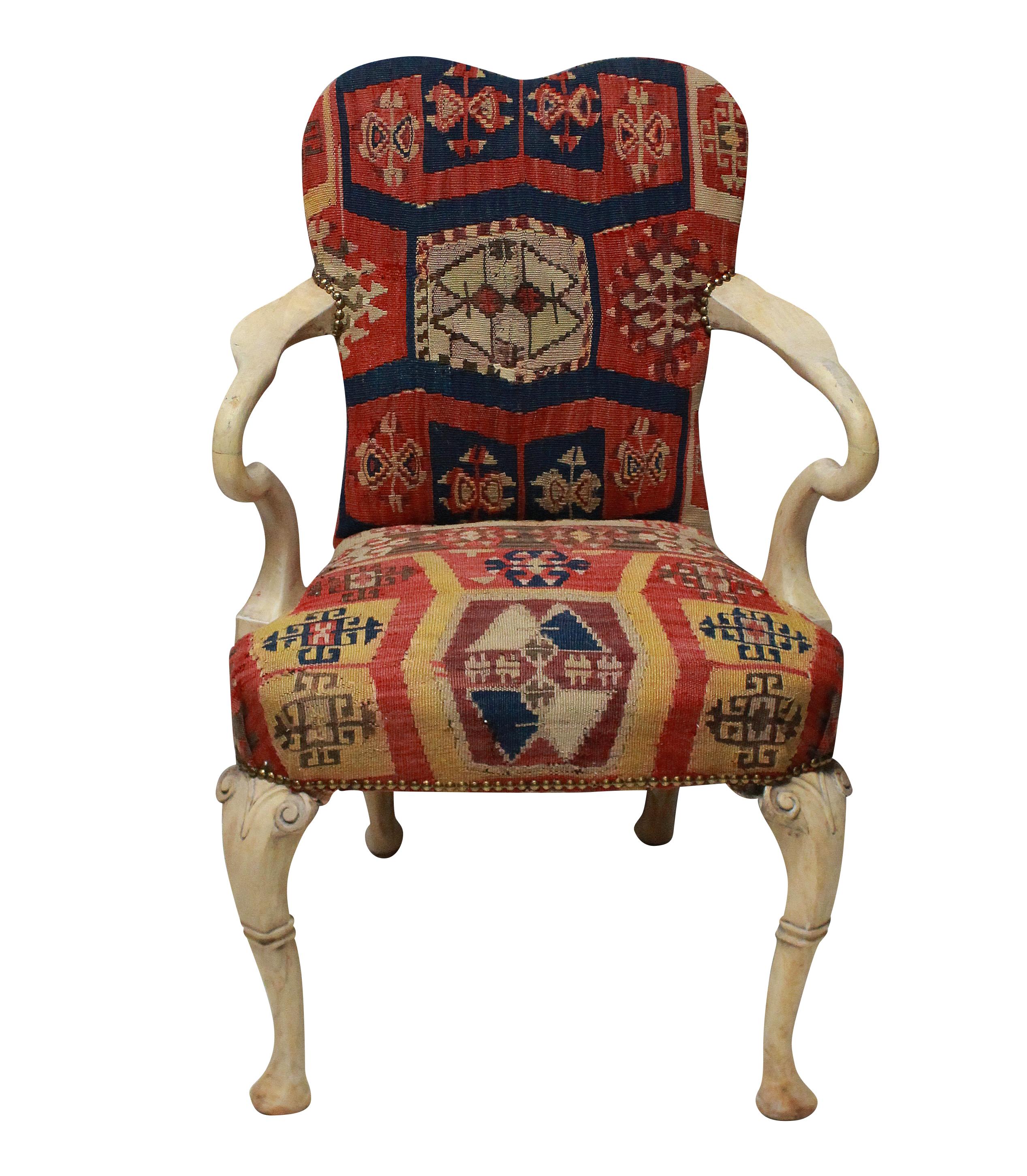 A pair of English armchairs attributed to Syrie Maugham. In 'pickled' wood, the armchairs are in the Queen Anne style and covered in a 19th century Kilim, with studding.