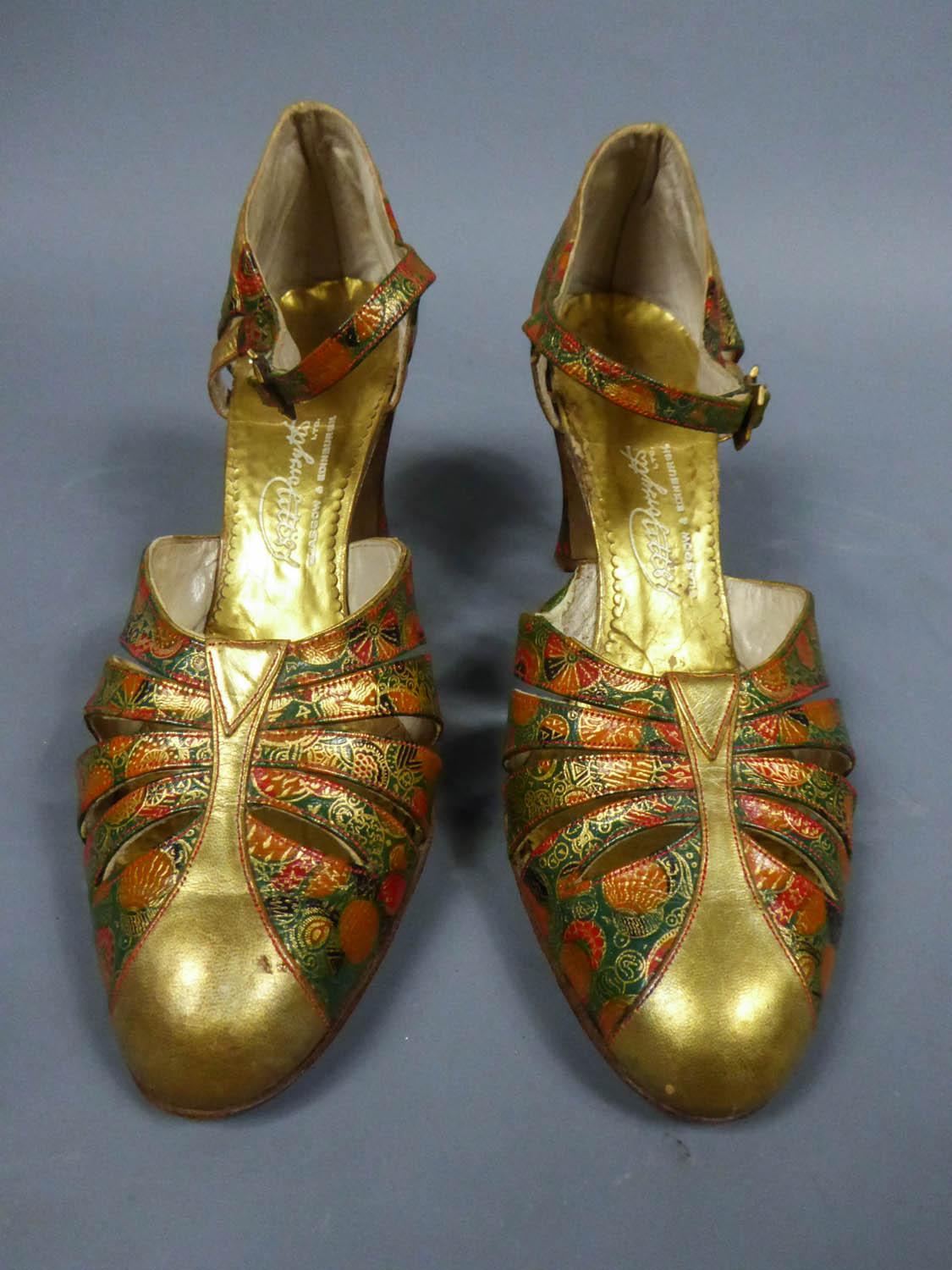 Circa 1930
Scotland

Heels or pair of T-bar shoes Salome for the ball dating from the Belle Epoque and Scottish origin. Printed and engraved leather with green, red, gold and black Art Deco pattern. Appliqués of golden leather. Gold and engraved