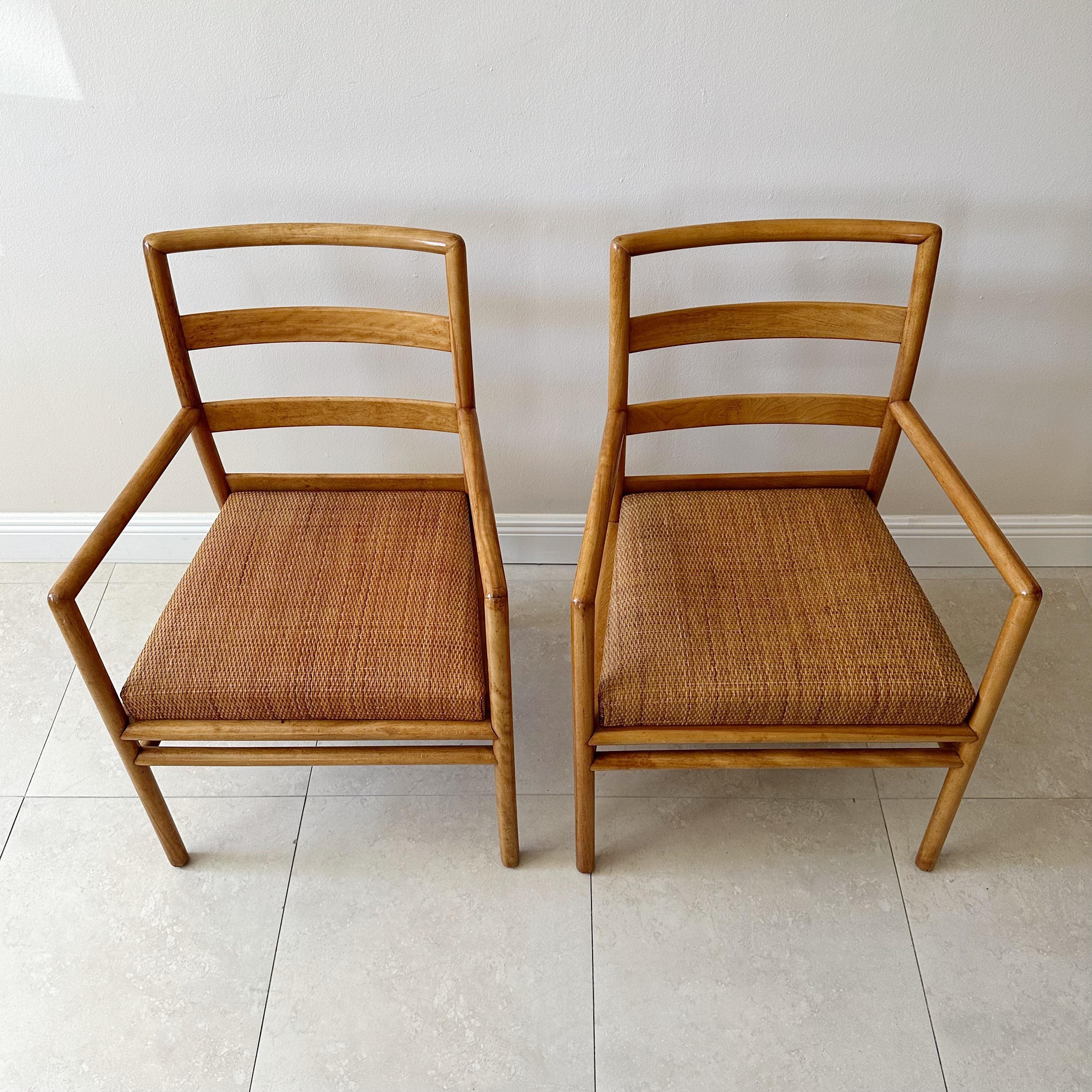 Pair of mid century armchairs by T. H. Robsjohn Gibbings for John Widdicomb. These chairs have light wooden frames, checkered rattan cane webbing seats, and ladder backs, resting on four dowel legs with stretchers.