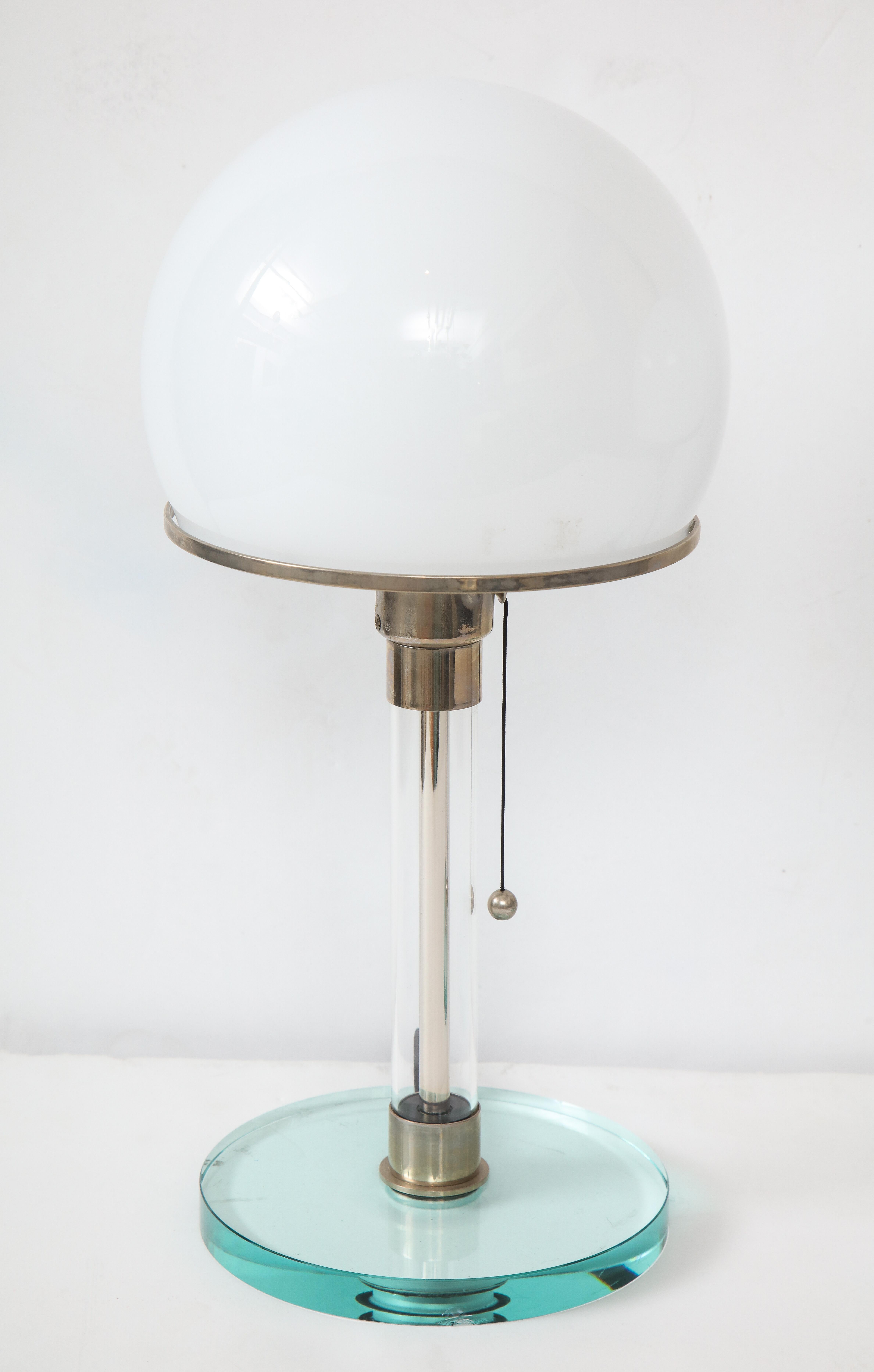 A pair of Bauhaus style table lamps designed by Wilhelm Wagenfeld and Karl Jucker on a blue Lucite base, chrome stem and domed glass shade in white.

??All lamps are consecutively numbered under the base and bear the Bauhaus and TECNOLUMEN