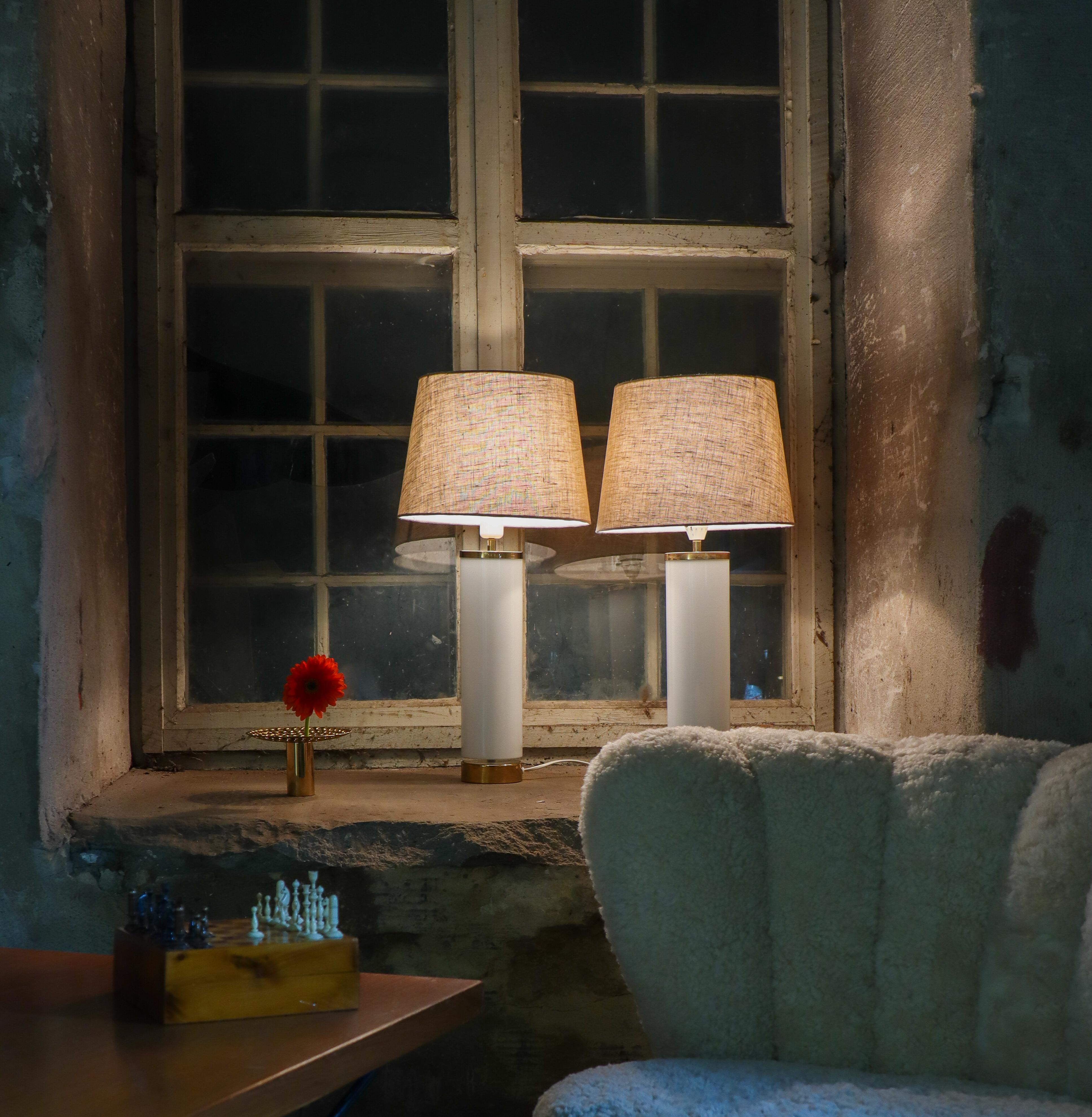 Paire d'élégantes lampes de table en verre blanc avec détails en laiton au sommet et à la base. Ces lampes ont été conçues et produites par Bergboms à Falkenberg, en Suède, probablement dans les années 1960. Sans les abat-jour, les bases mesurent 47