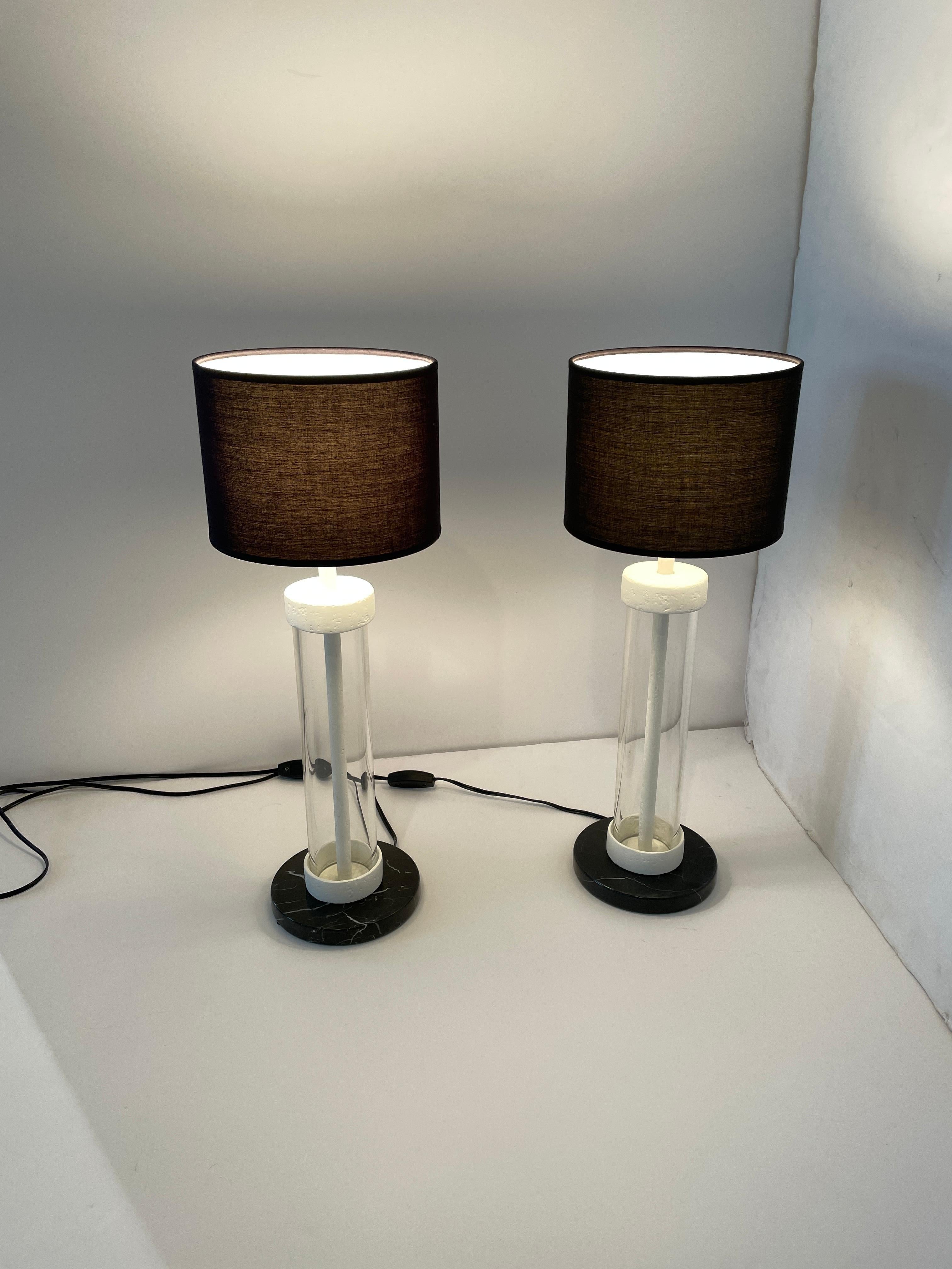 Two one of a kind table lamps with Belgium black marble bases, glass tube bodies and plaster of paris accents. The lights are topped with a black linen shade. Great for side tables, bed side tables. The contrast with the black and white elements