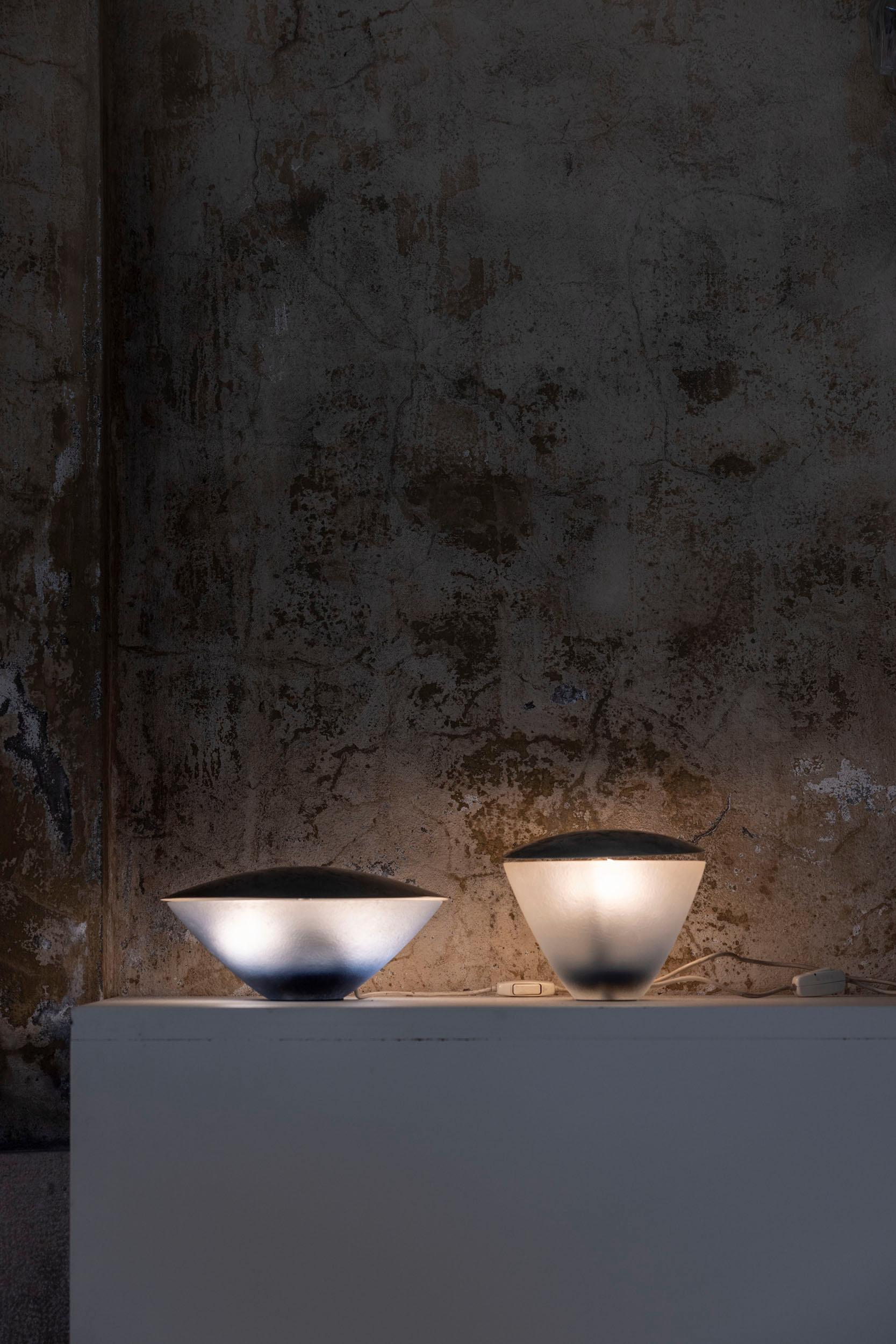 Rare pair of table lamps by C. Emanuele Ponzio for Venini, featuring two sizes with blue and white hand blown glass bodies topped by a steel plate. 
These lamps provide a soft, diffused light, blending elegance and functionality. 
Published on Domus