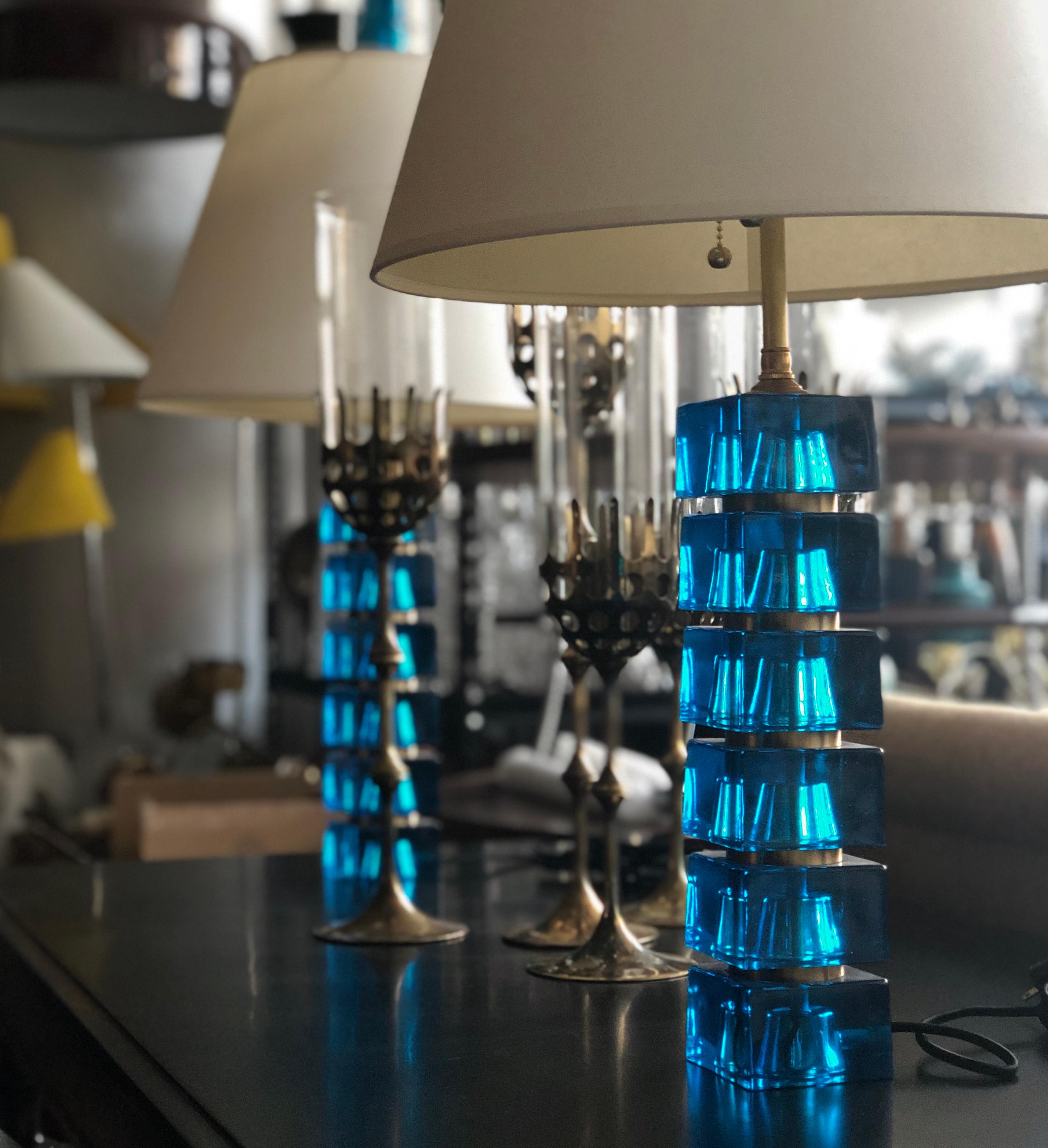A pair of table lamps by Carl Fagerlund for Orrefors, Sweden, circa 1960s.
Blue glass cubes and brass fittings. Measures: Glass base height 13.75