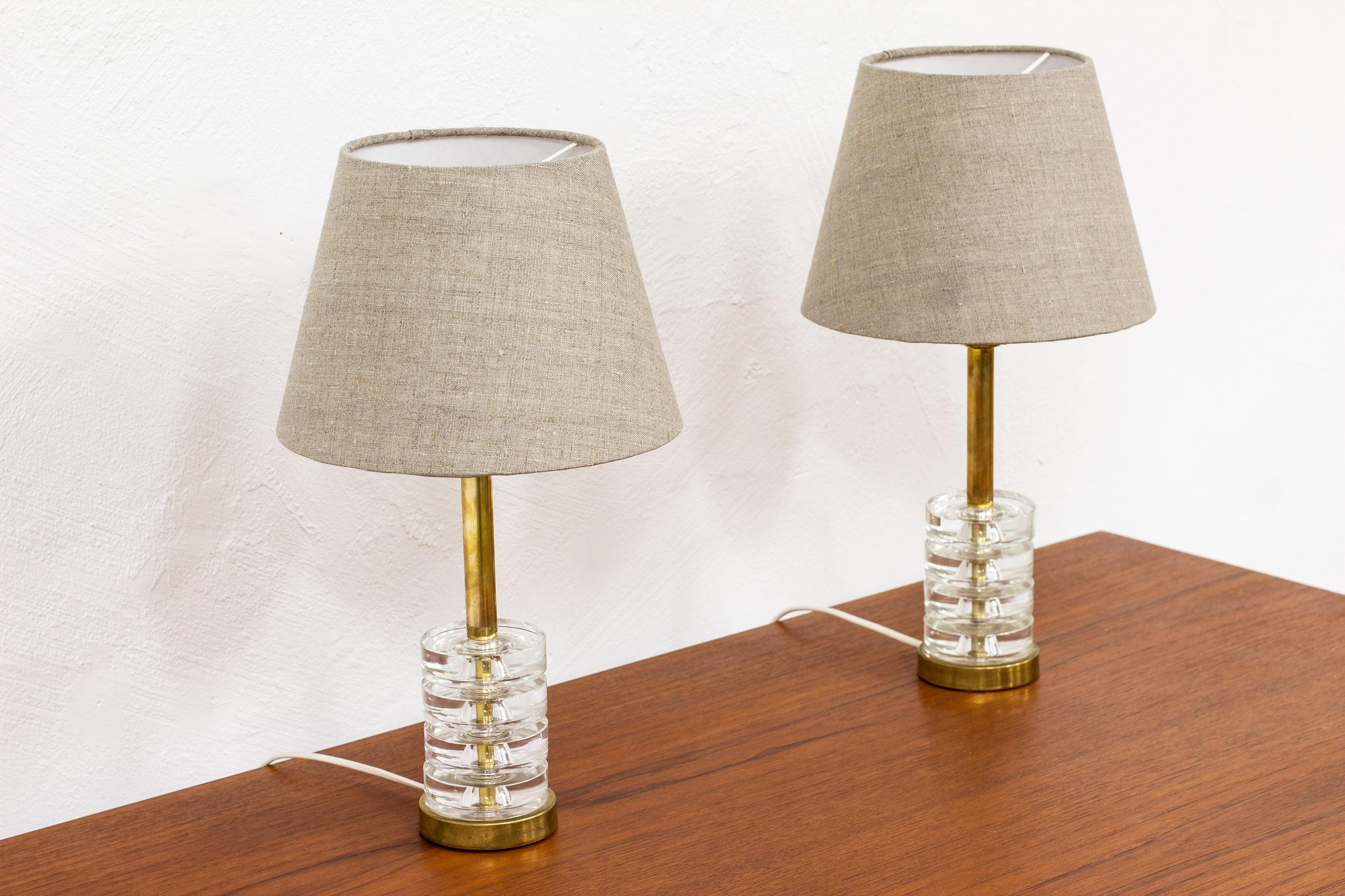 Pair of table lamps model RD 1981 designed by Carl Fagerlund. Produced in Sweden by Orrefors during the 1950s. Made from brass and several thick clear glass discs. Light switches on the lamp holder in working order. very good vintage condition with