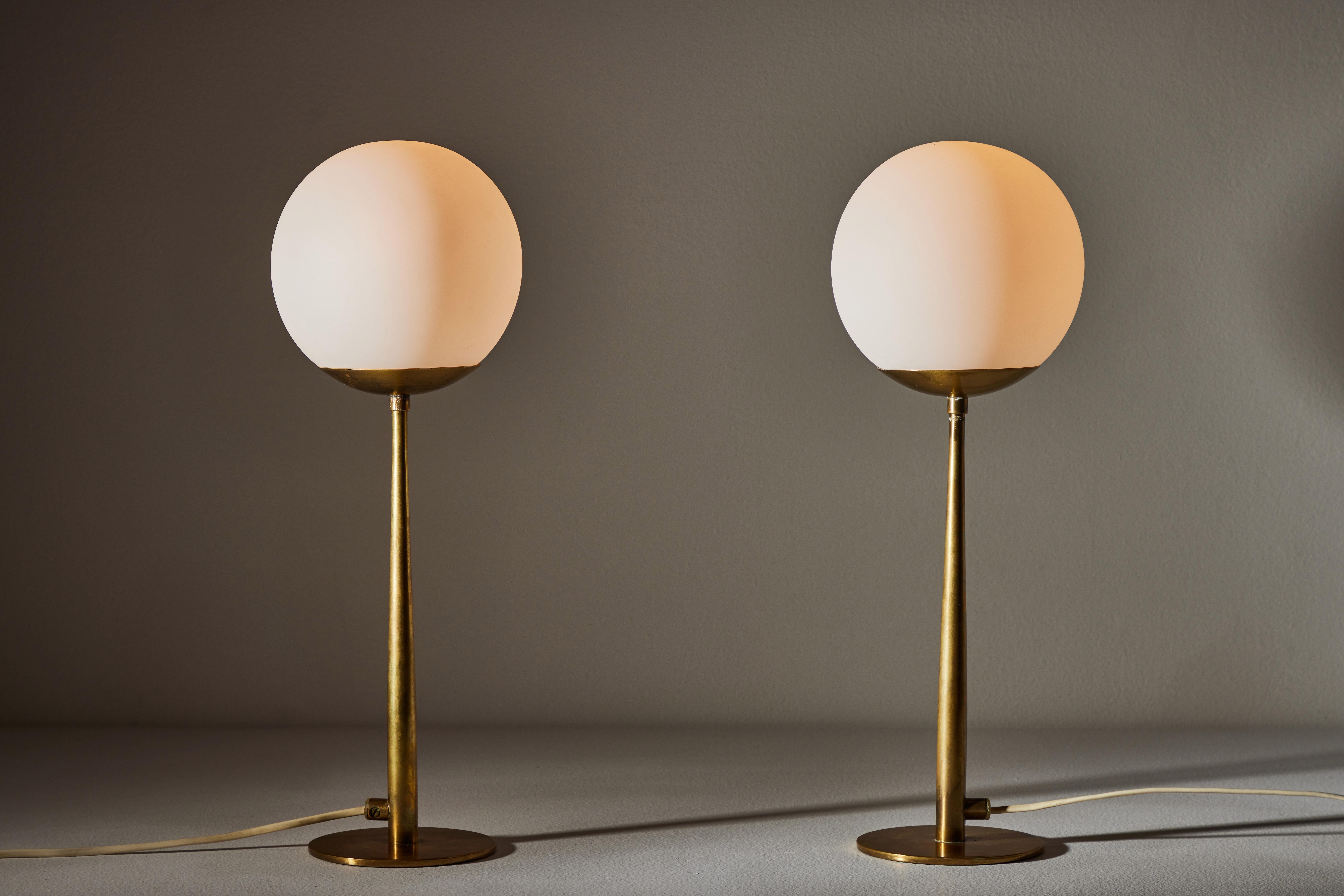 Rare pair of table lamps by Hans-Agne Jakobsson. Designed and manufactured in Sweden, circa 1950s. Opal glass diffusers, brass stems. Original European cords. We recommend one E27 60w maximum bulb per fixture. Bulbs provided as a one time
