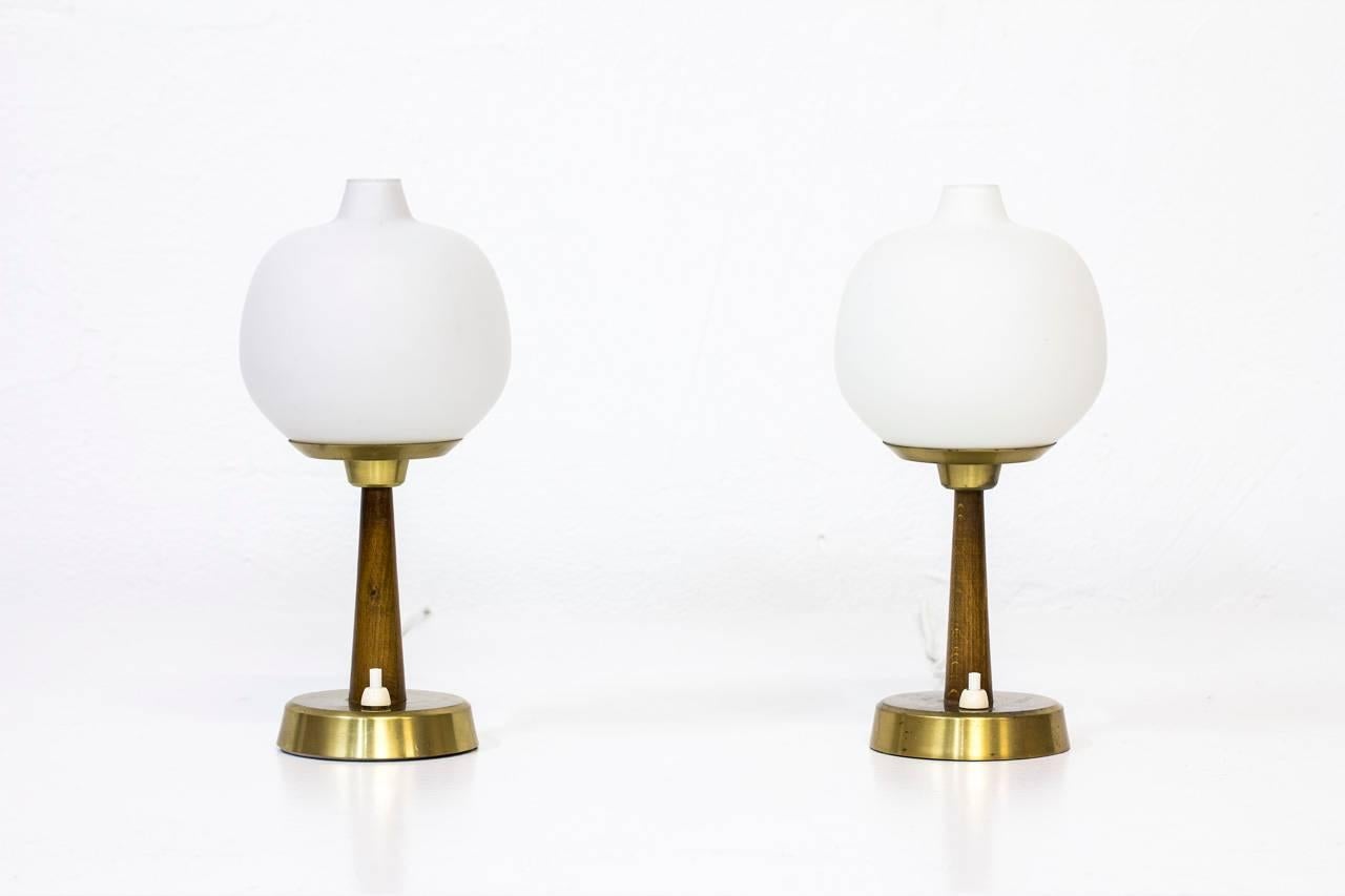 Pair of table lamps model 702 designed by Hans Bergström. Produced by his own company Ateljé Lyktan in Åhus, Sweden in the 1950s. Stained beech stem with brass base and support. Opaline glass shade. Light switch on the base.