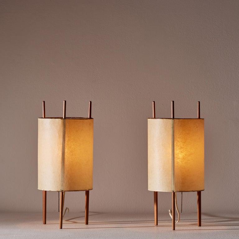 Pair of table lamps by Isamu Noguchi for Knoll. Manufactured in U.S. circa early 1950's. Parchment paper shade, cherrywood frame. Original cord that works with U.S. sockets. We recommend one E27 60w maximum bulb per fixture. Bulbs not provided.