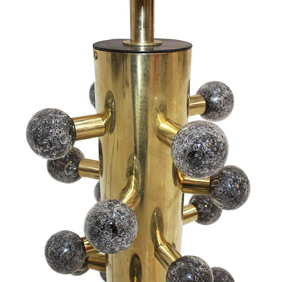 Contemporary maximalist brass table lamps, a stunning blend of modern design and opulence. This exquisite lamp features a cylindrical polished brass structure adorned with spherical Murano colored in grey glass pieces, adding a touch of vibrancy and
