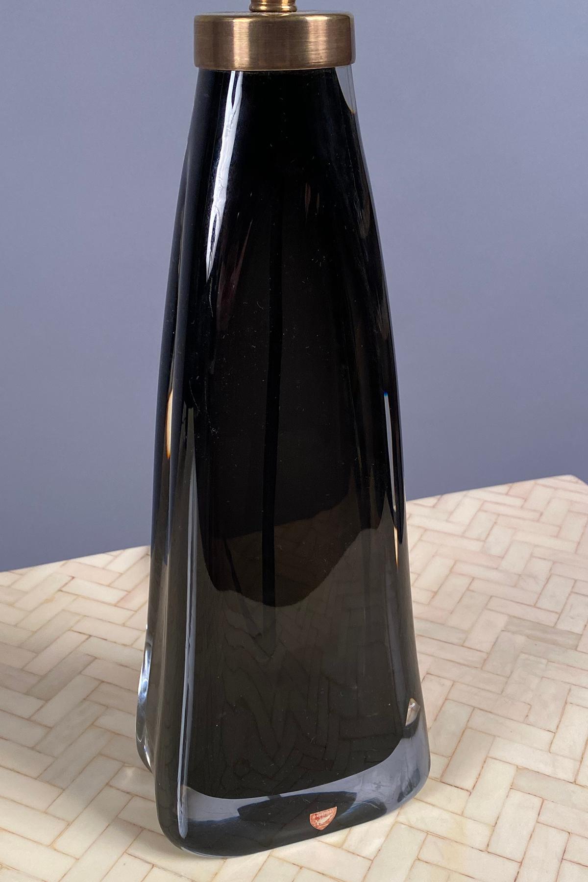 Dark gray glass with a clear glass exterior and slightly in-curving sides. Stamped on the bronze fitting; and with original label. 
 