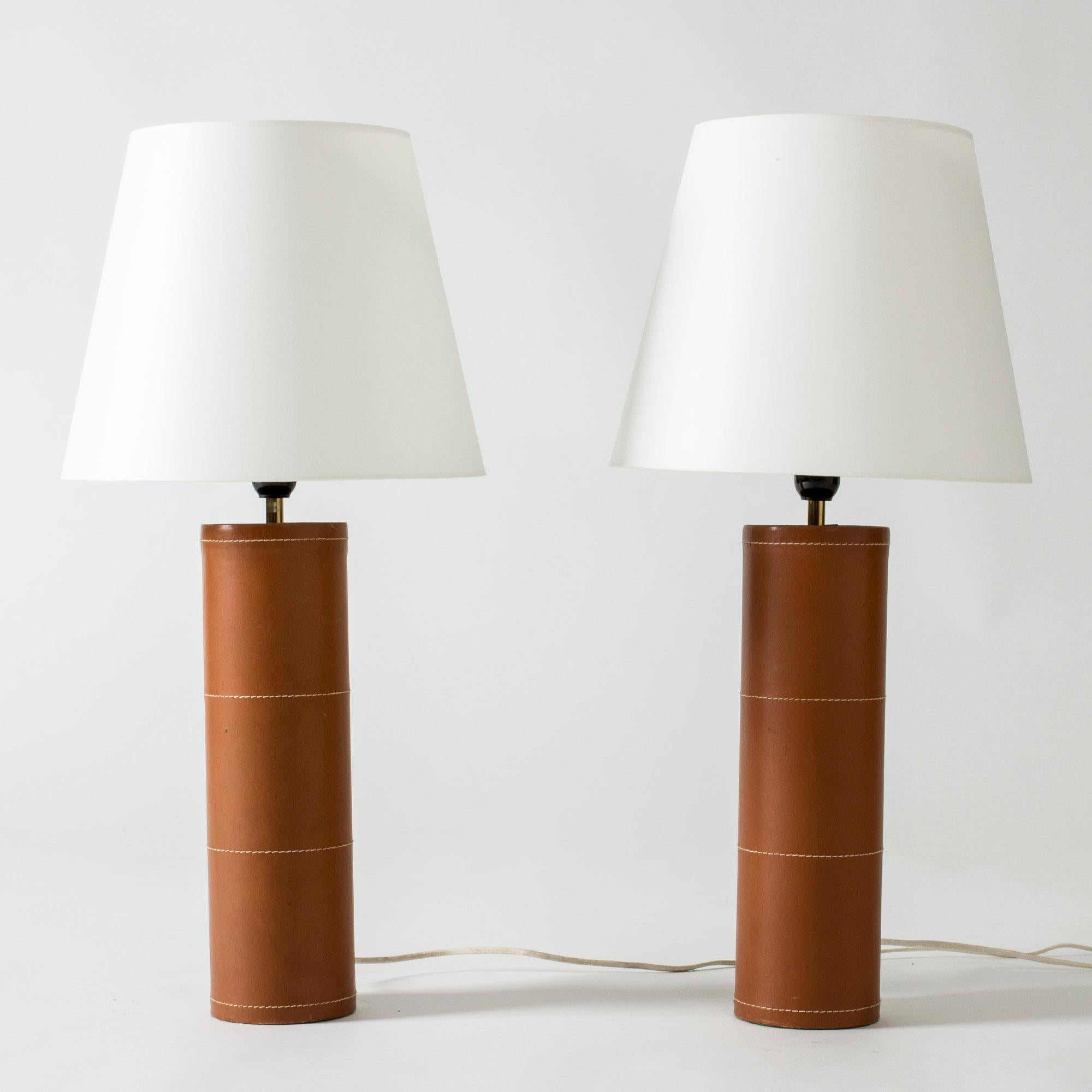Pair of large table lamps from Bergboms with cylinder bases dressed in cognac leather. Decorated with white seams – a minimalist design with a deluxe finish.