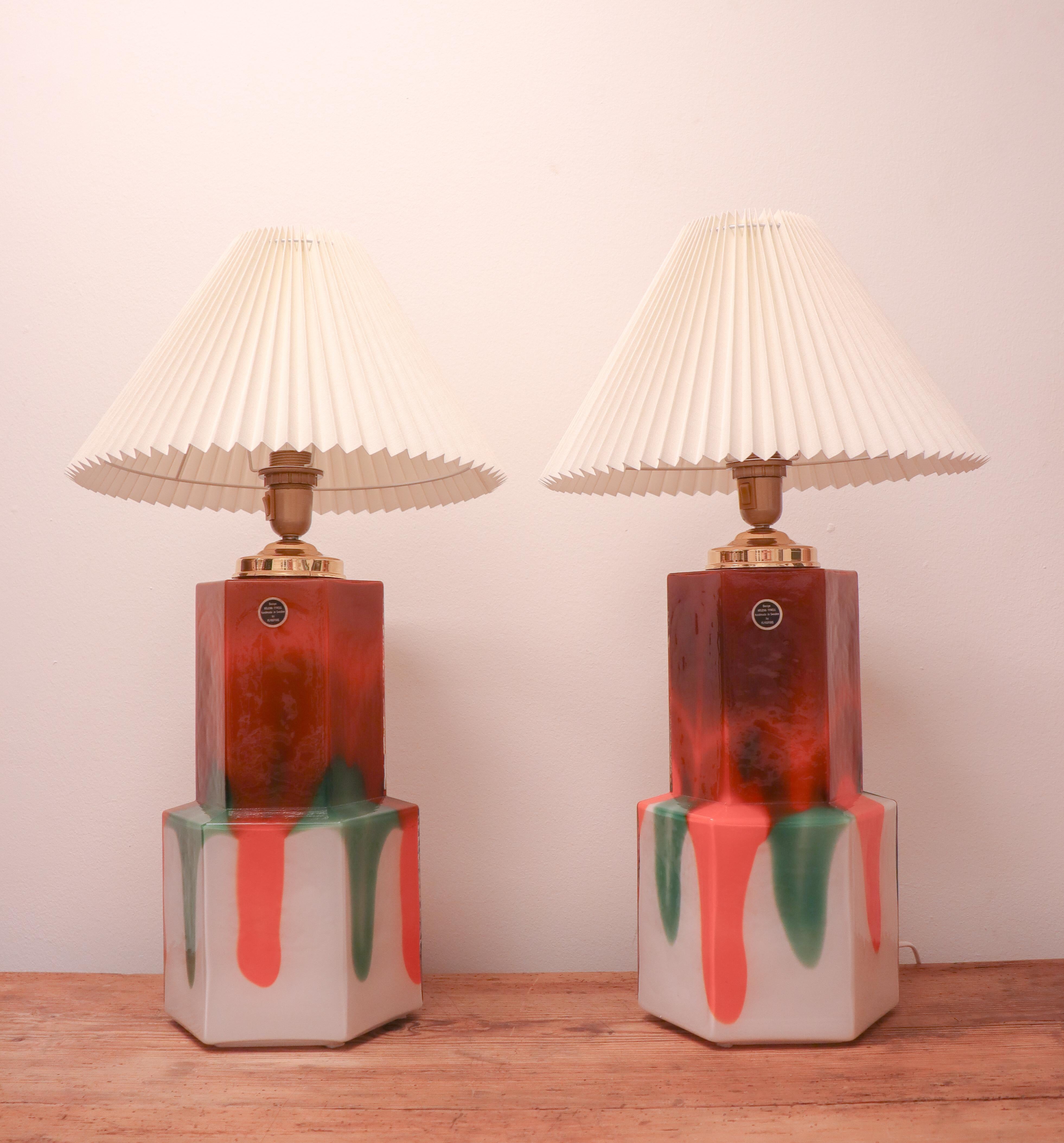 A pair of table lamps in glass designed by Helena Tynell att Flygsfors glassworks in Sweden in the 1970s. Excluding the lampshades they are 51 cm high and about 18 cm in diameter. They are both label-marked and in excellent condition. 
