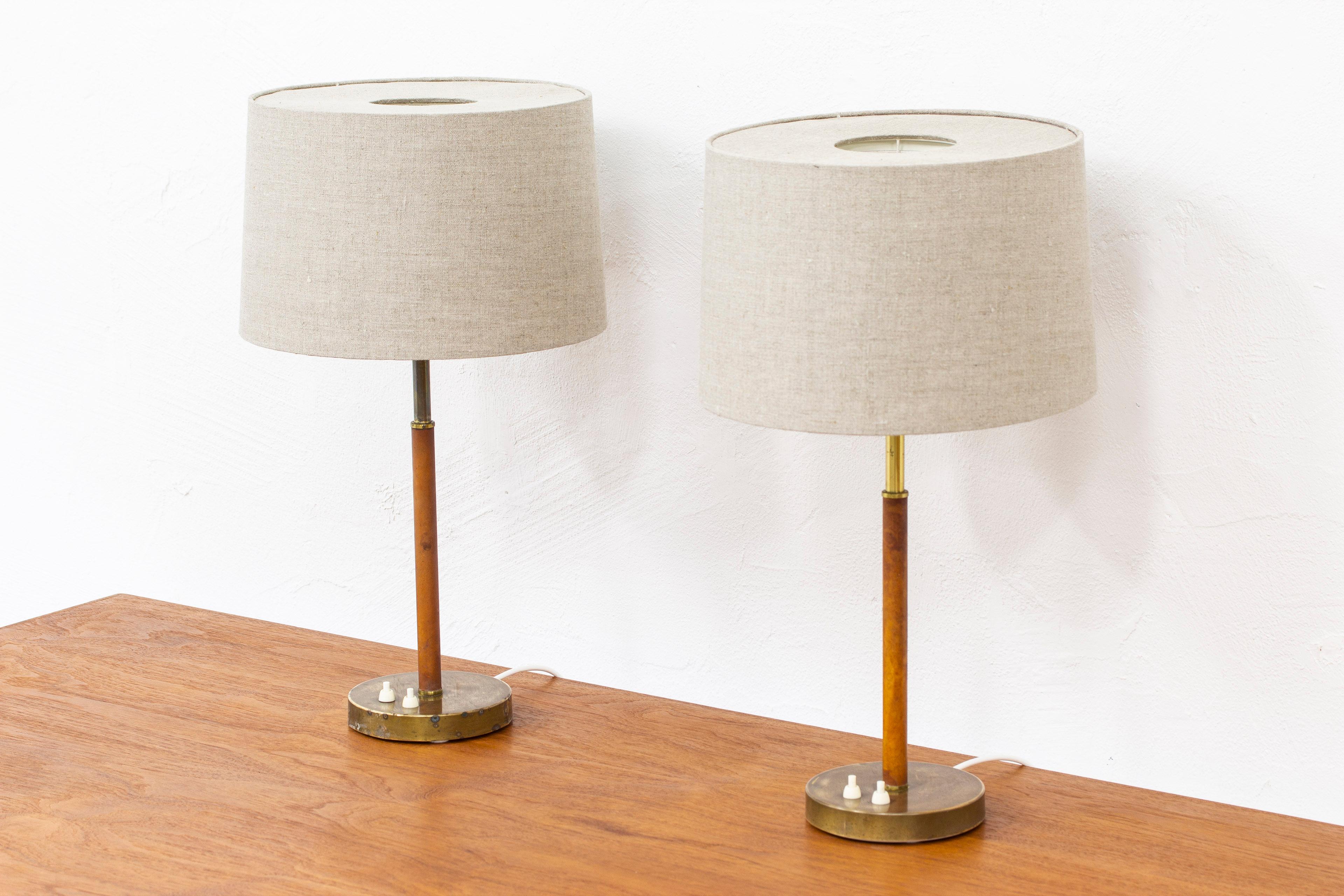 Pair of table lamps model 2043 designed by Bertil Brisborg & Åke Hultgren. Produced in Sweden by Nordiska Kompaniet during the 1950s. Made from brass, white lacquered metal and with original cognac colored leather. The original lamp shades have been