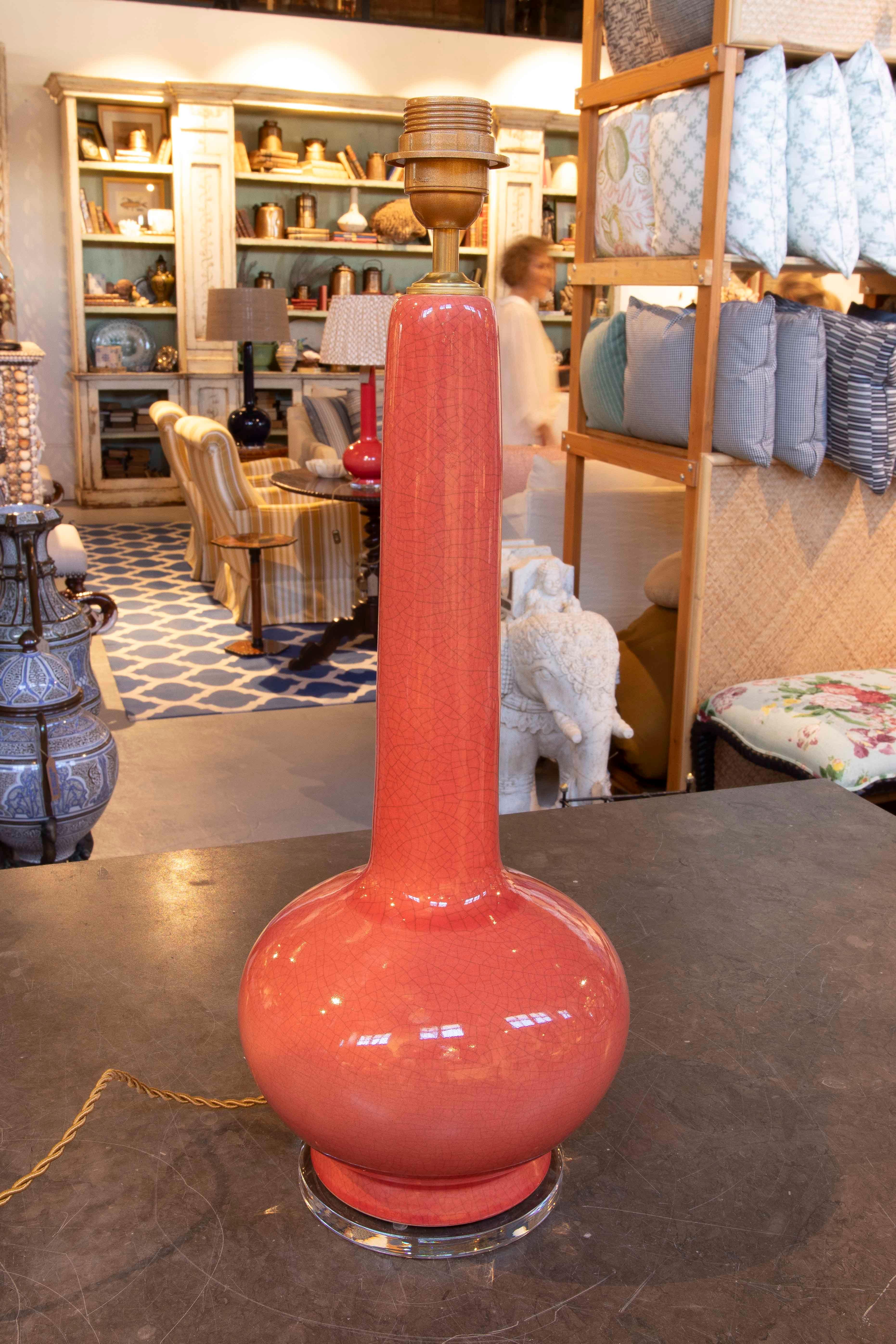 A refined pair of table lamps crafted from glazed ceramic in an elegant pinkish coral hue, with a crackled finish that adds texture and sophistication. Their design combines a globular base with a tall, slender neck, evoking the shapes of oriental