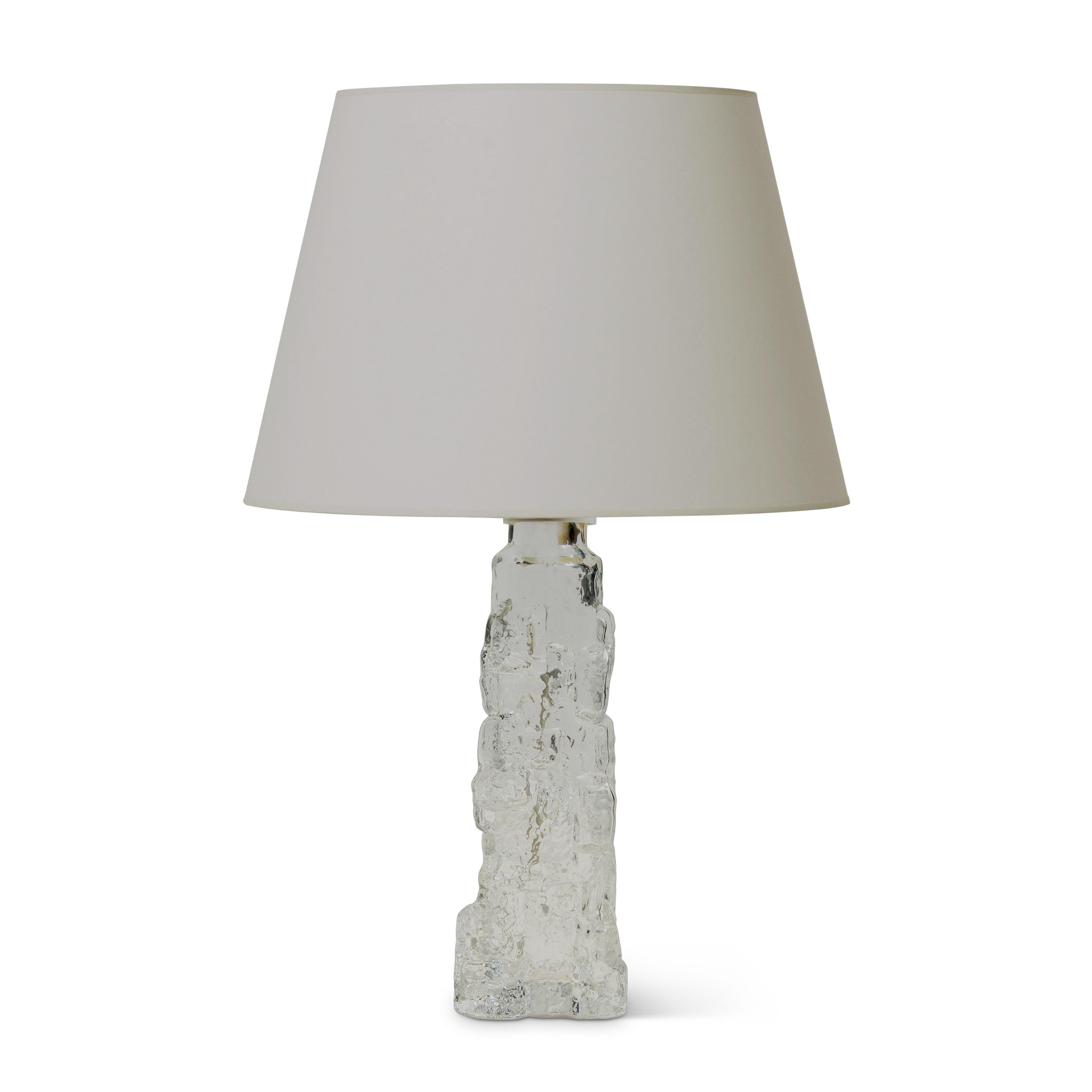 Table lamps (pair and single available) evoking rocky outcroppings by Reijmyre Glasbruk, having a tall upwardly tapered triangular base modeled with rocks and crags that catch light and create a marvellous shimmer across the surface when lit,