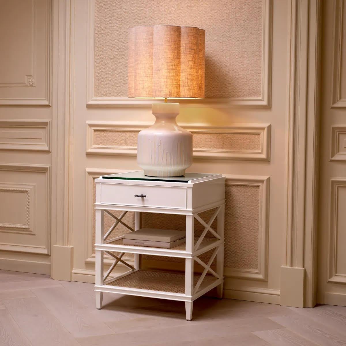 Discover the charm of this table lamp, a ceramic marvel with a captivating white drop effect finish.
Its custom-made linen blend lampshade enhances its artistic essence, while vintage brass accents add a touch of elegance. Perfect for discerning