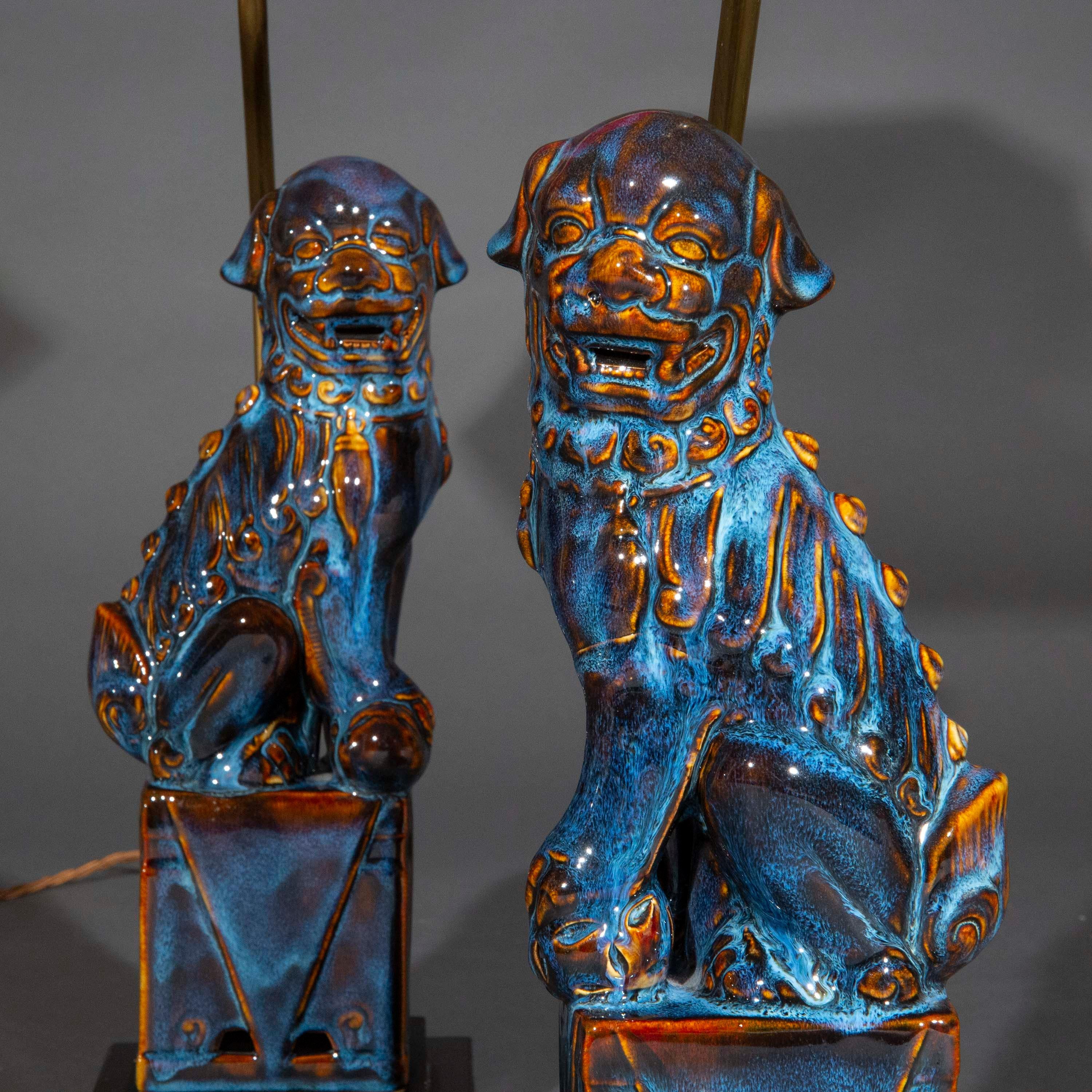 Fabulous pair of table lamps featuring wonderfully decorative ceramic figures of foo dogs, or buddhist temple lions, beautifully glazed with purple and blue streaks (flambé).

We love the opulence of colours and the intricate pattern of the glaze.