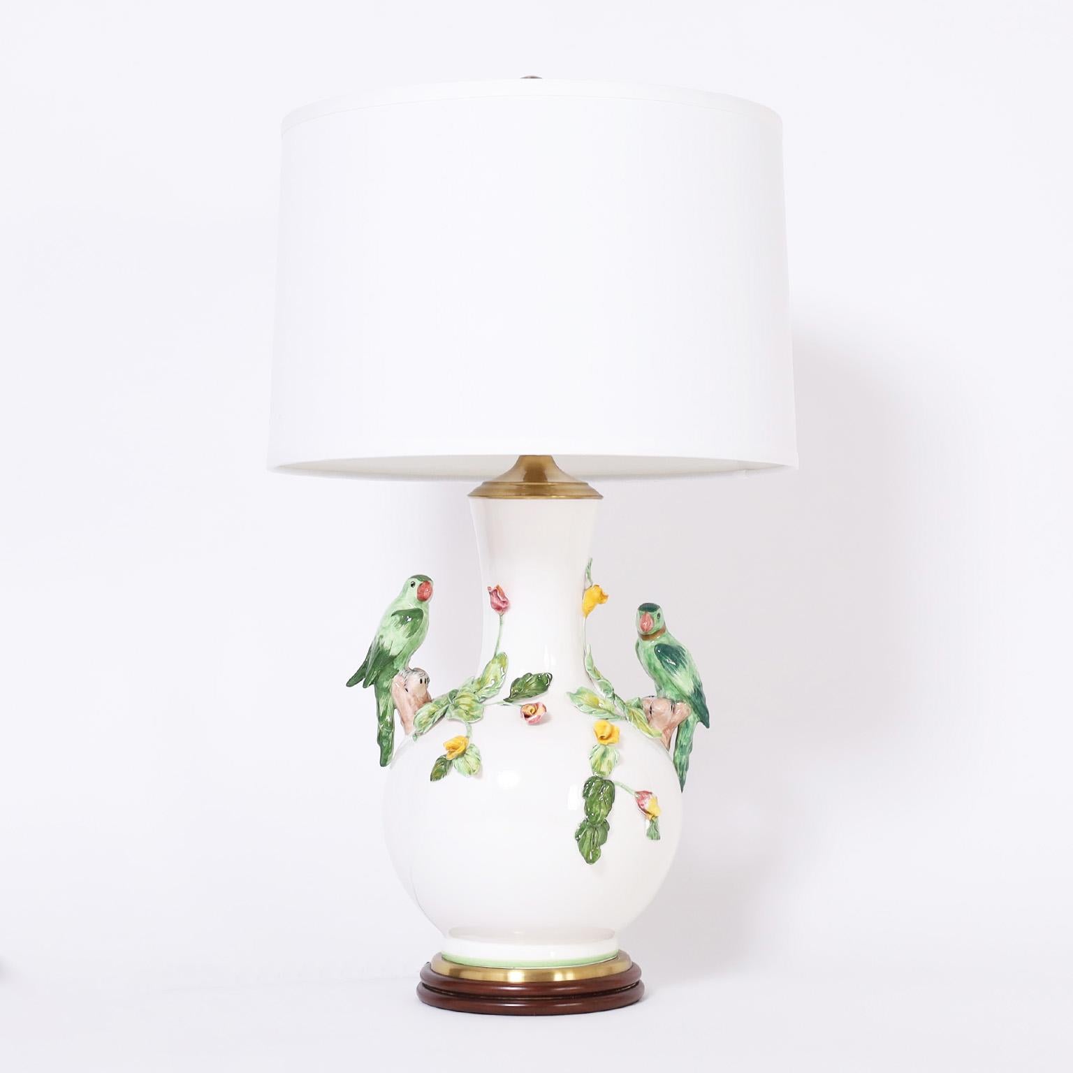 Charming pair of porcelain table lamps decorated with tropical colored parrots and flowers against a blanc de chine background. Signed Wildwood on the sockets and presented on turned mahogany bases.