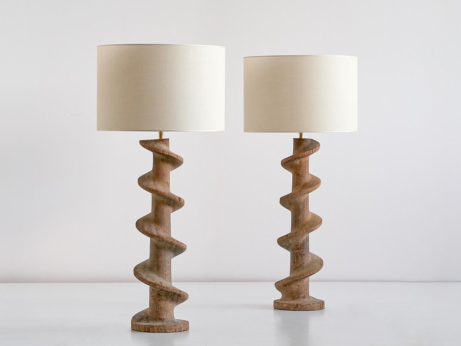 A unique pair of large table lamps consisting of a striking spiral screw base and custom fabric shades. 

The substantial concentric hardwood spirals were used in the textile industry in the southern part of Belgium in the late 19th century. The