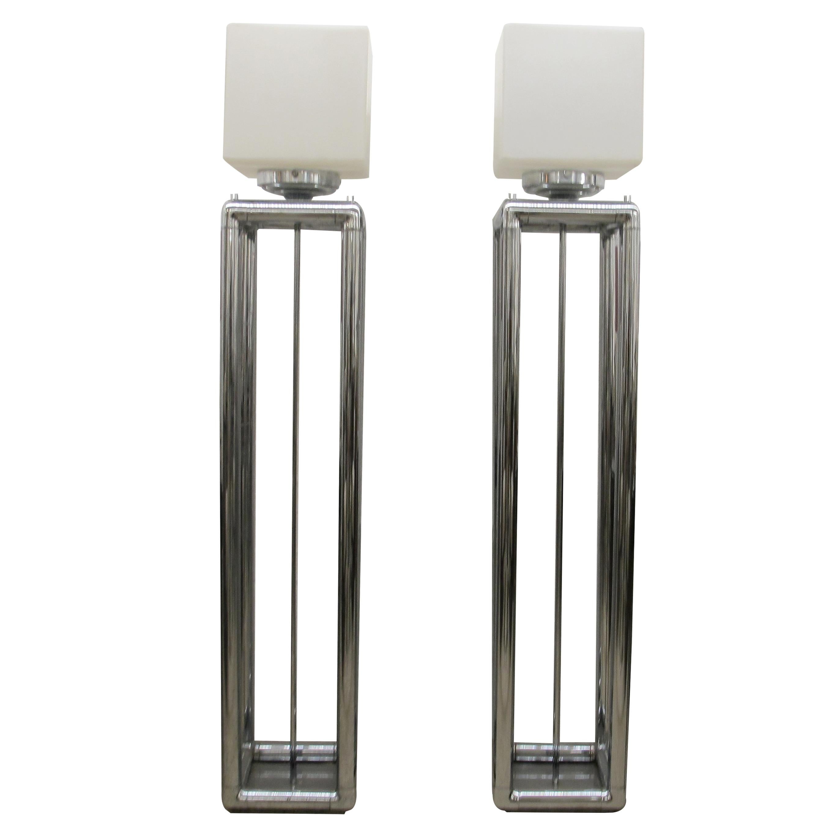 This pair of floor lamps was made in England in the 1970s. Each lamp has a tall, open rectangular base constructed from polished chrome. The design is simple and geometric, typical of mid-century modern and 1970s styles. Both lamps feature frosted