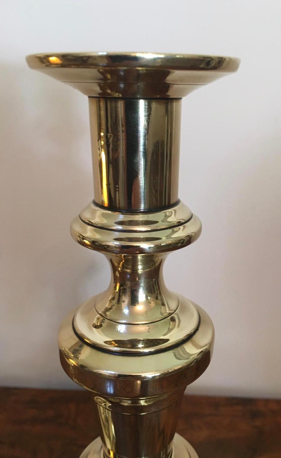 Pair of tall antique brass candlesticks with a lovely shaped column rising from a shaped stepped bases, each still retain their original push ejector rod.

 