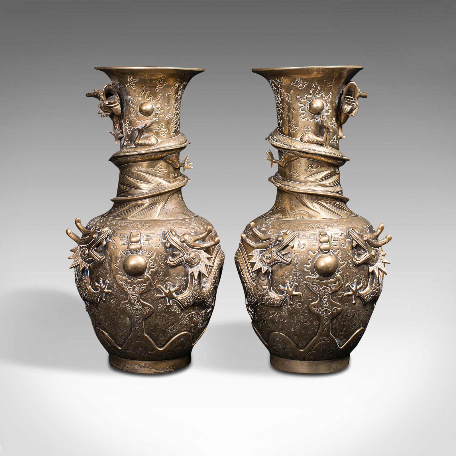 This is a pair of tall antique dragon vases. A Chinese, brass decorative flower urn with strong Oriental taste, dating to the Victorian period, circa 1900.

Strikingly overt in detail and iconography
Displays a desirable aged patina