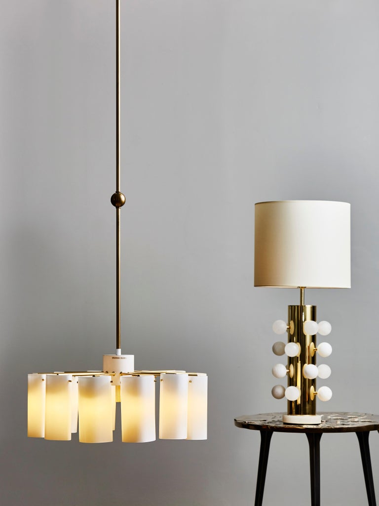 Pair of very tall Ark chandelier by Gert Nyström for Fagerhults Belysning made of a metal center piece, twelve brass arms and opaline glass shades. The chandelier is suspended by an adjustable tall brass stem.