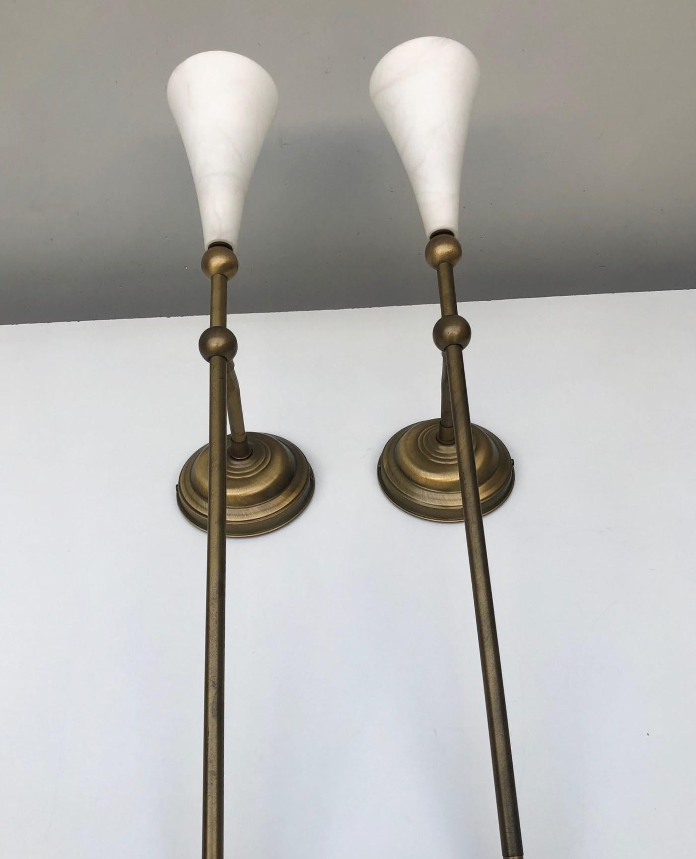 Pair of tall Art Deco torchiere wall sconces, France 1930s. Very elegant design made of bronzed brass with conical white alabaster shades. Each sconce takes one Edison E14 candelabra screw bulb. 
In very good vintage condition, no damages, beautiful